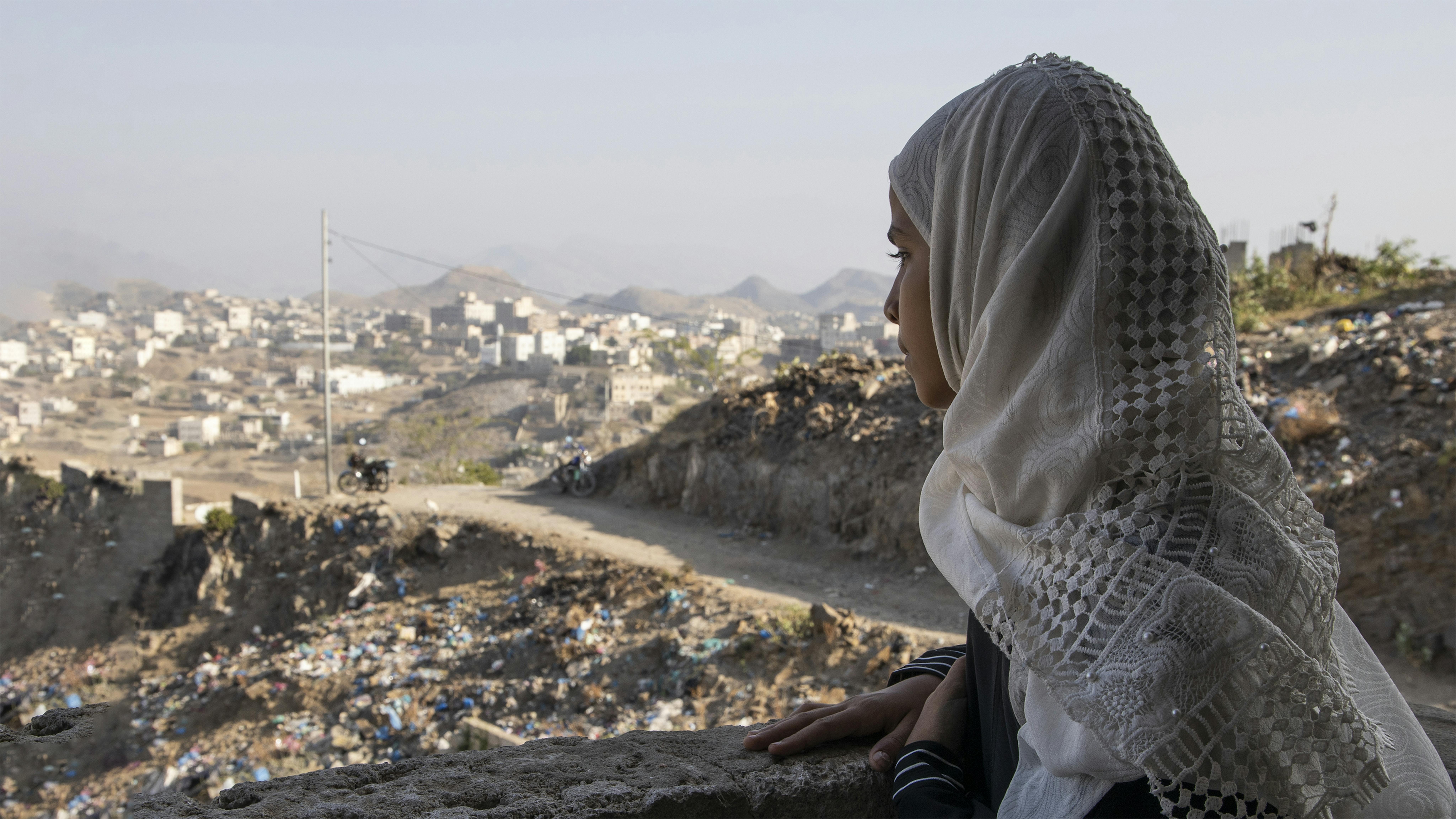 Yemen, una ragazza guarda le rovine della città di Taizz dalla sua scuola dove fa lezioni