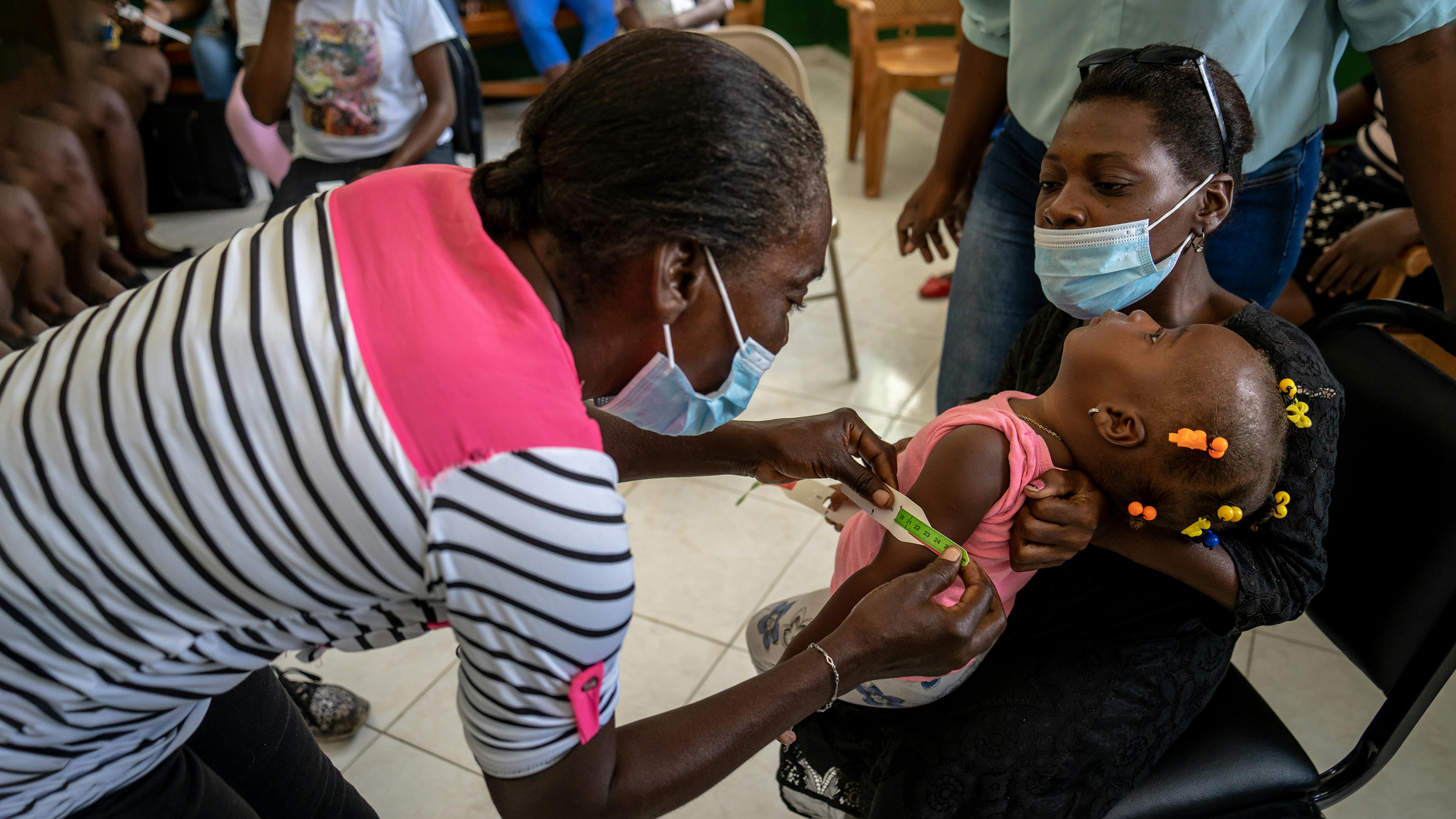 Haiti, un operatrice comunitaria  verifica lo status della malnutrizione a una bambina nella clinica Cavallion