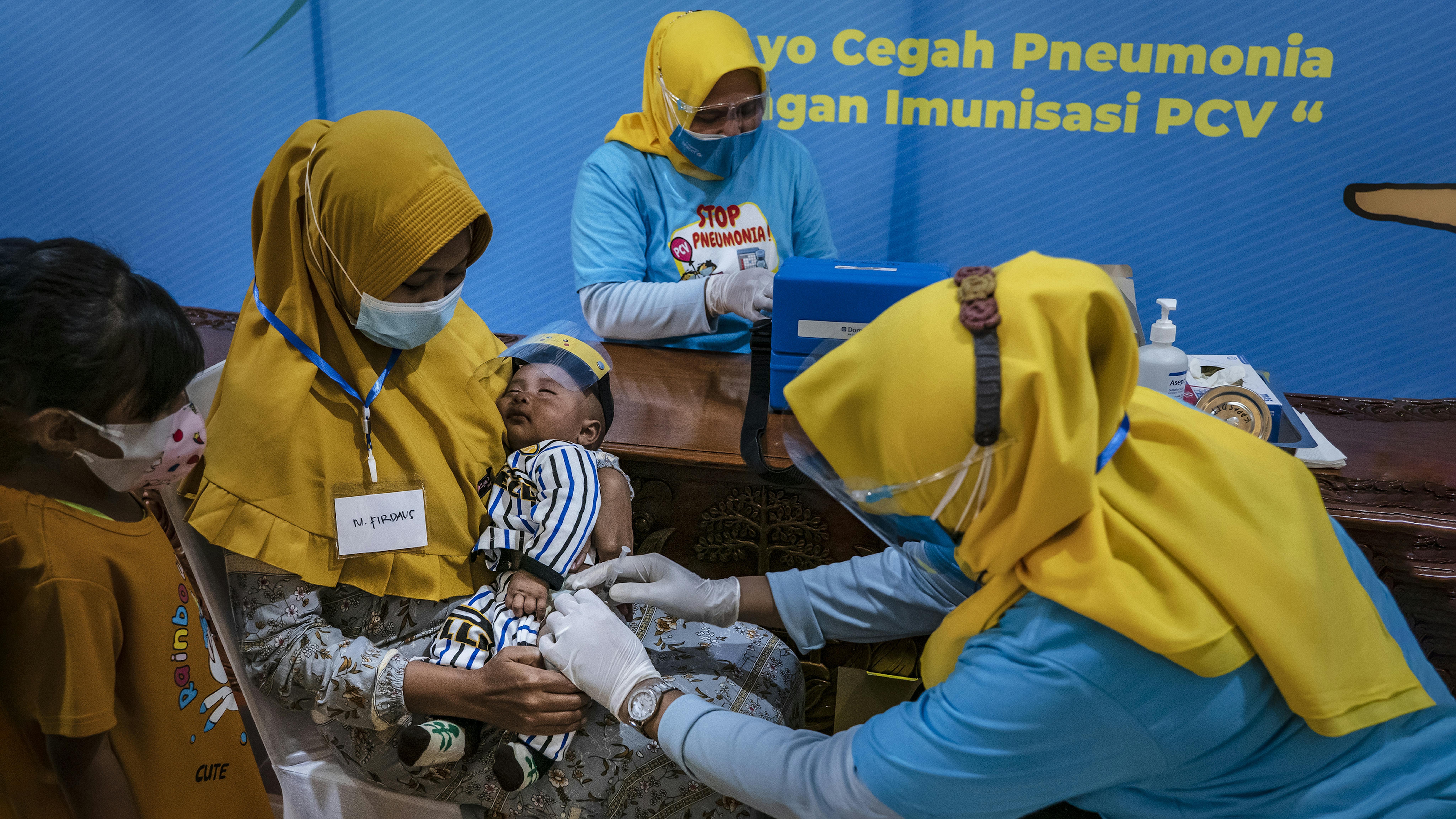 Indonesia, Uul Masula, 28 anni, tiene in braccio il suo bambino Firdaus mentre riceve una dose del vaccino pneumococcico