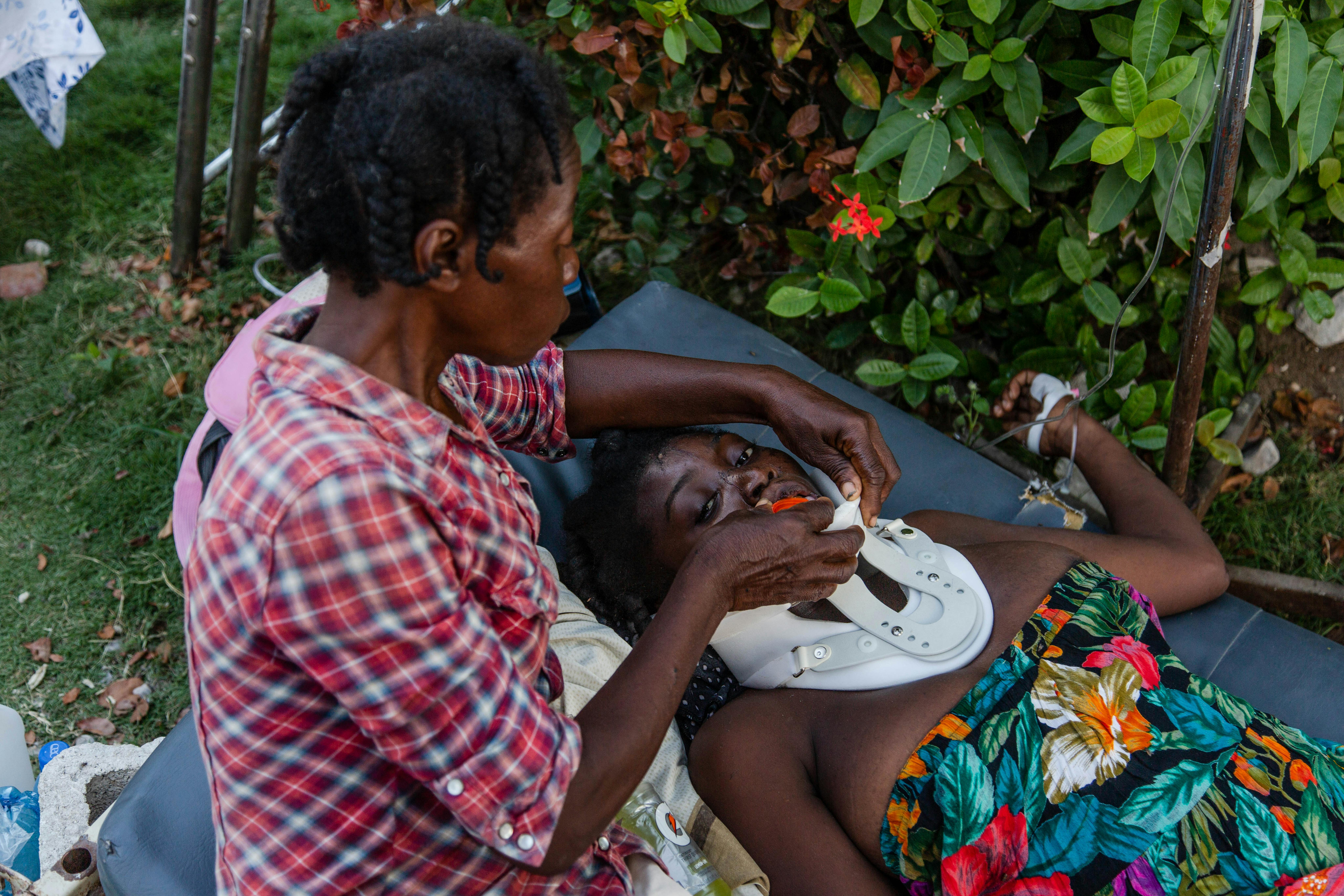 Gerline, una donna rimasta paralizzata al seguito del crollo della sua casa durante il terremoto di Haiti, viene aiutata da un'amica a reidratarsi