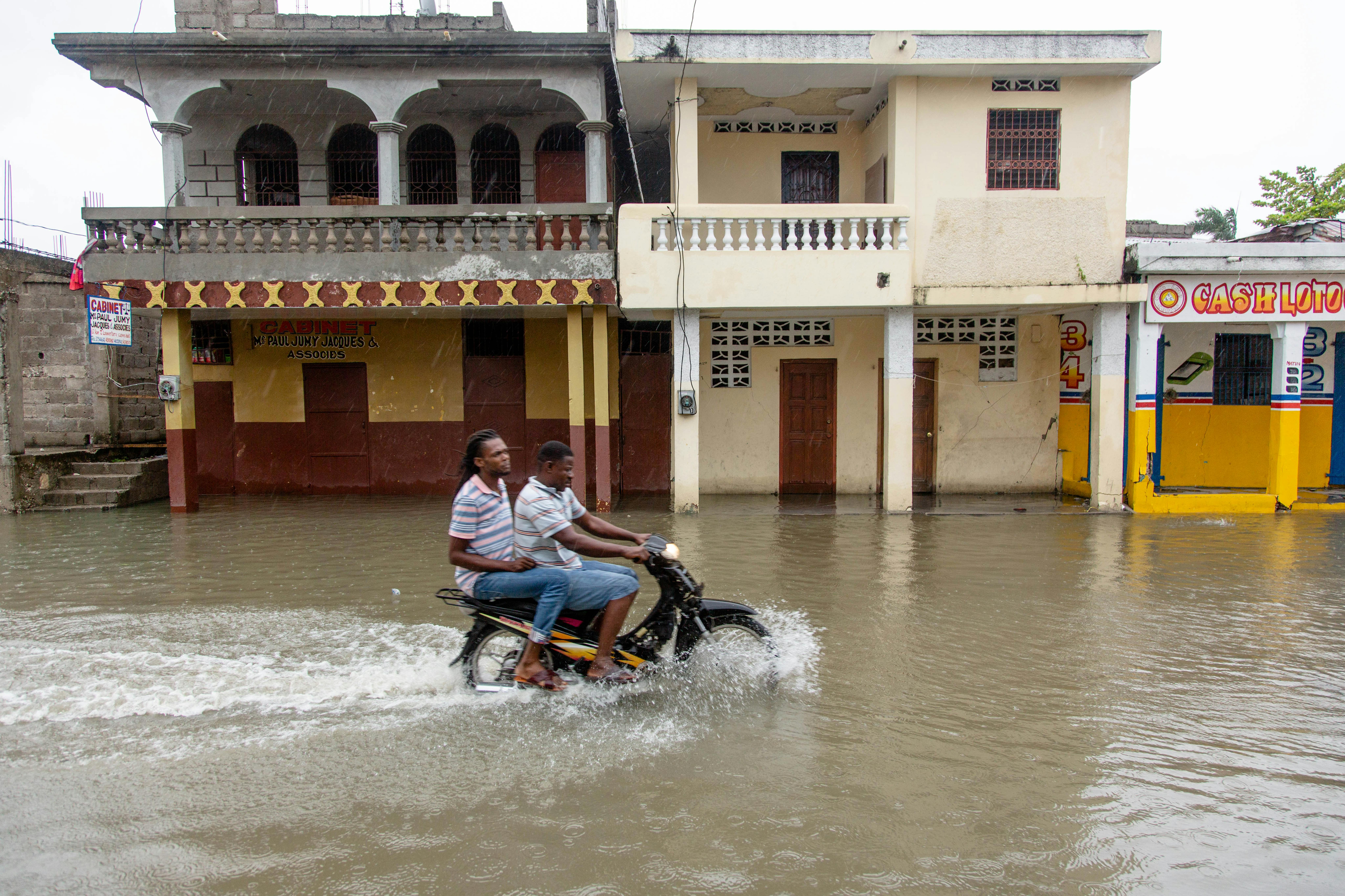 Due uomini viaggiano in moto attraverso le strade allagate a causa della tempesta tropicale Grazia a Les Cayes, Haiti il 17 agosto 2021.