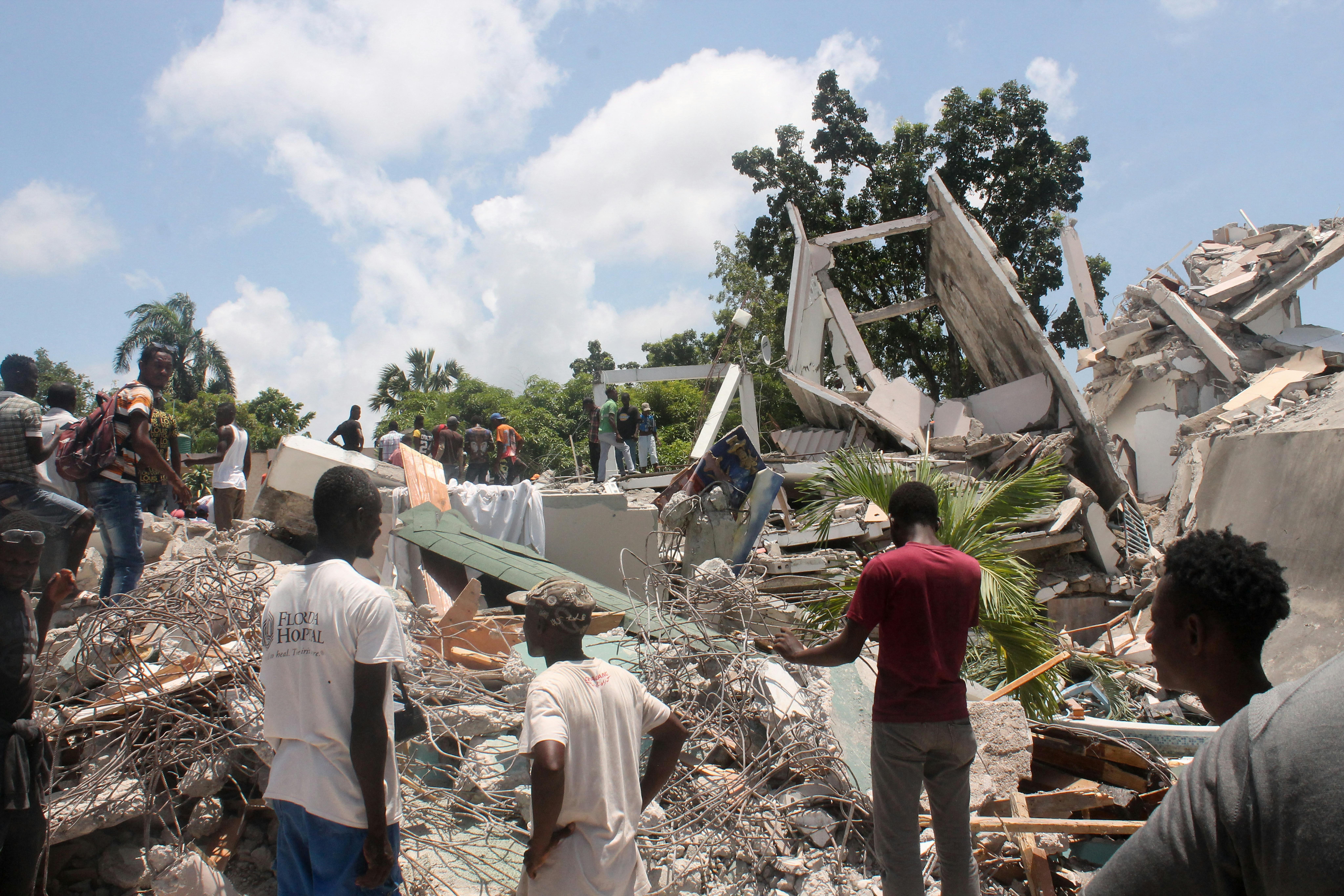 Alcune persone cercano tra le macerie di quello che resta del Manguier Hotel a seguito del terremototo. Siamo a Les Cayes, nel sud-ovest di Haiti.  