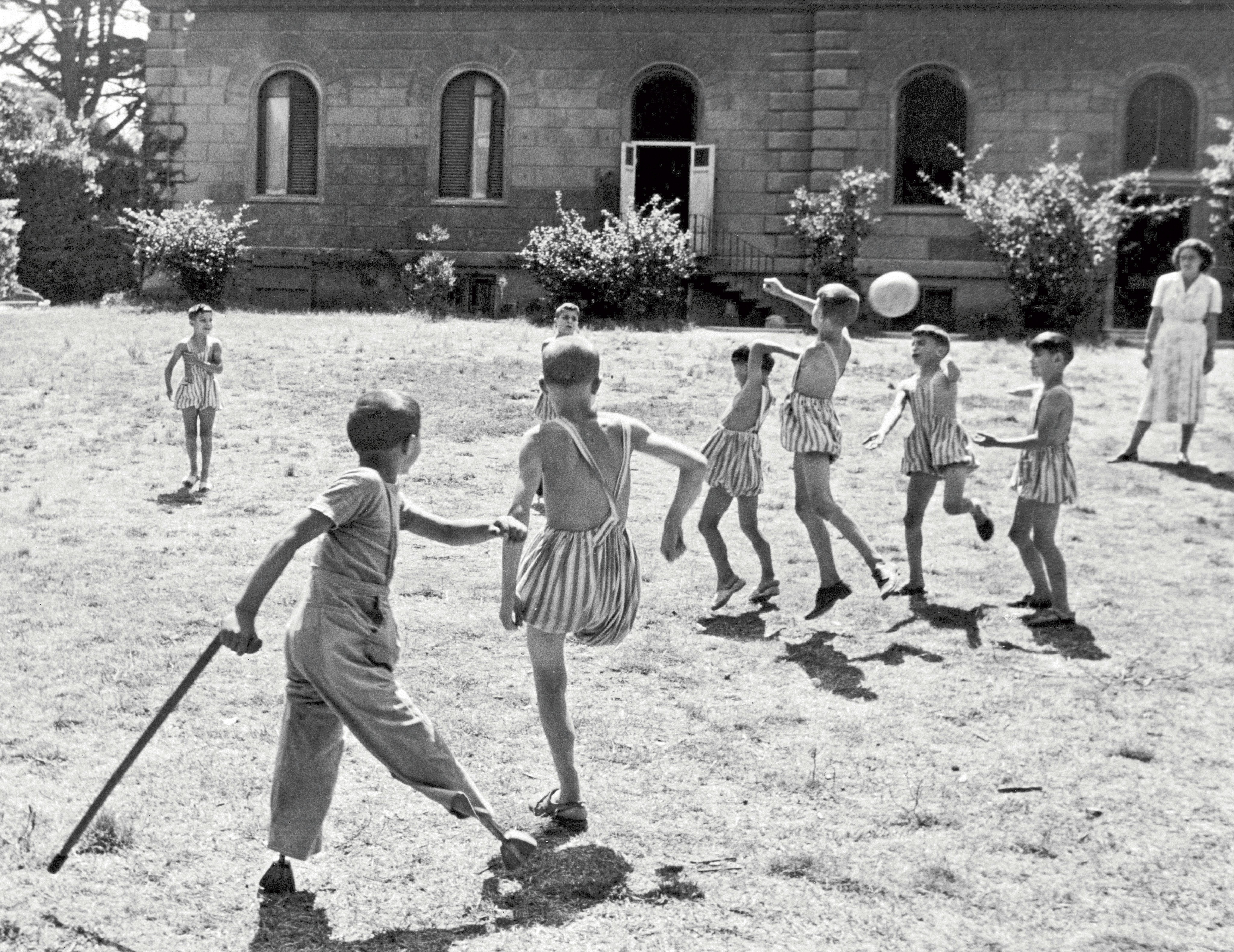 Italia, 1950 circa: alcuni ragazzi disabili, molti dei quali senza un arto, giocano a pallone nel cortile di fronte ad un istituto