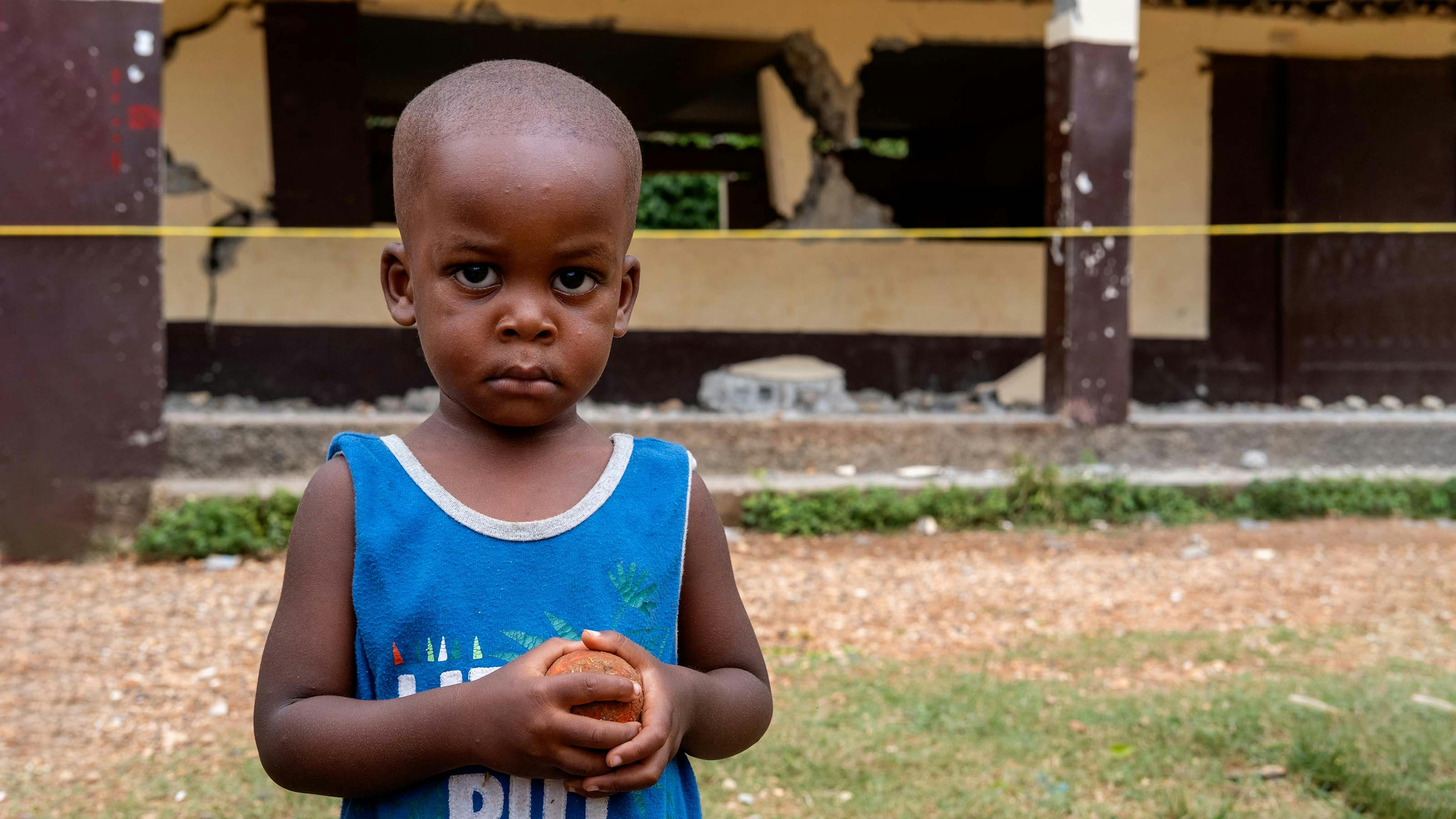 Un bambino si trova di fronte alla sua scuola distrutta durante il terremoto del 2021 ad Haiti.