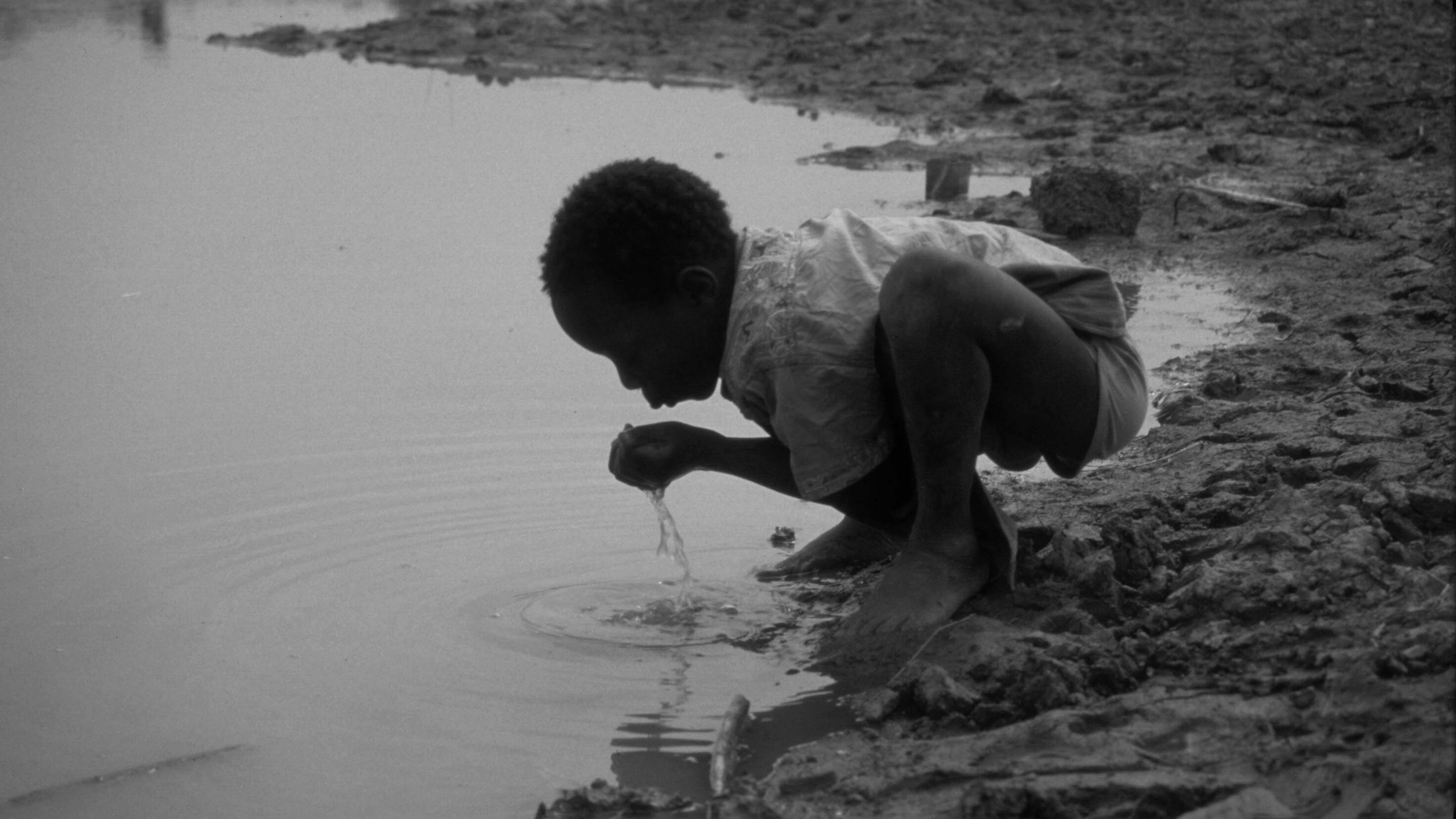 1984, carestia nel Sahel e nel Corno d'Africa: un ragazzo beve da uno stagno contaminato, unica fonte d'acqua disponibile nel villaggio di Zitenga, Burkina Faso.