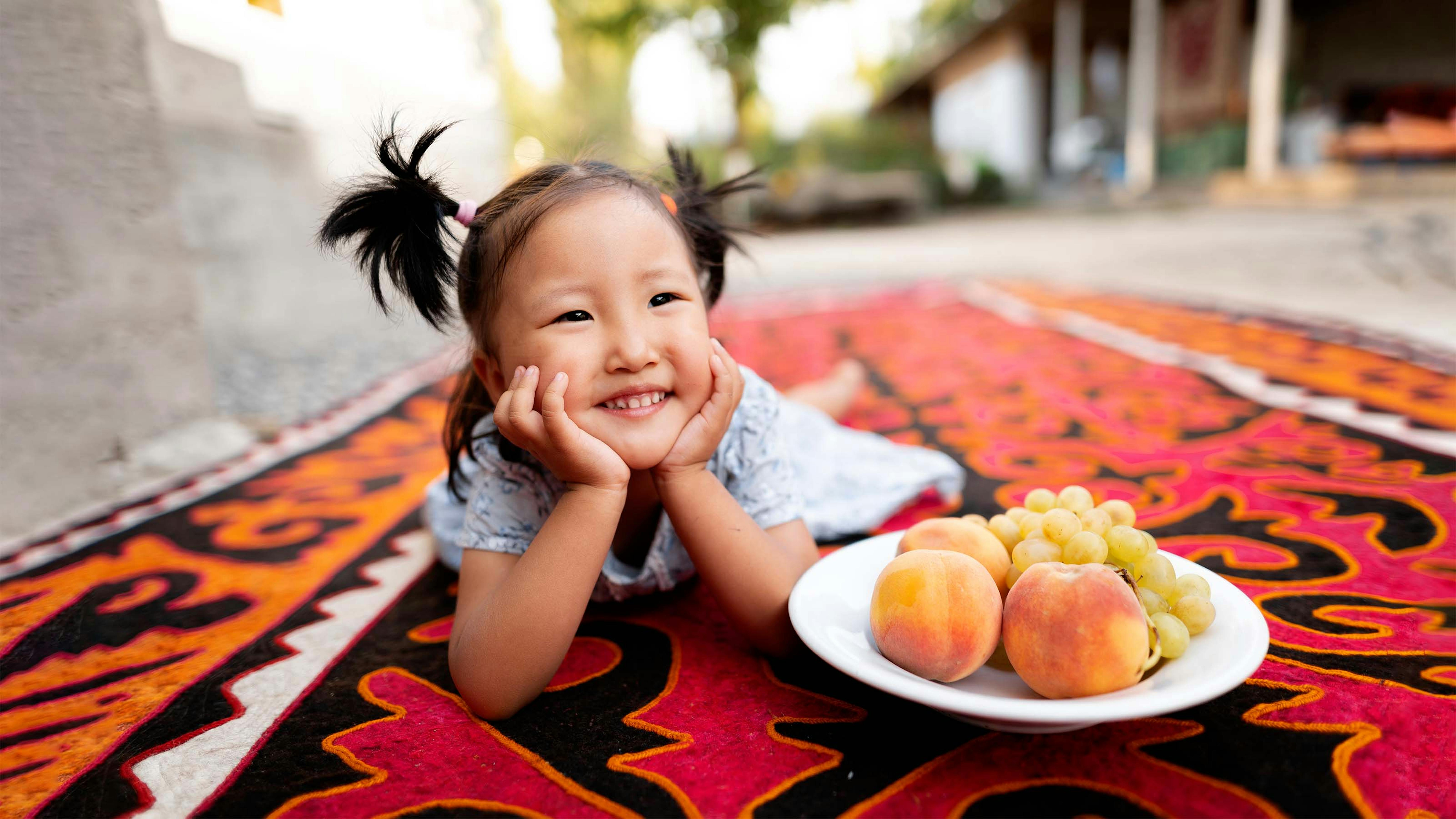 Kyrgyzstan, una bambina con un piatto di frutta, pieno di vitamine