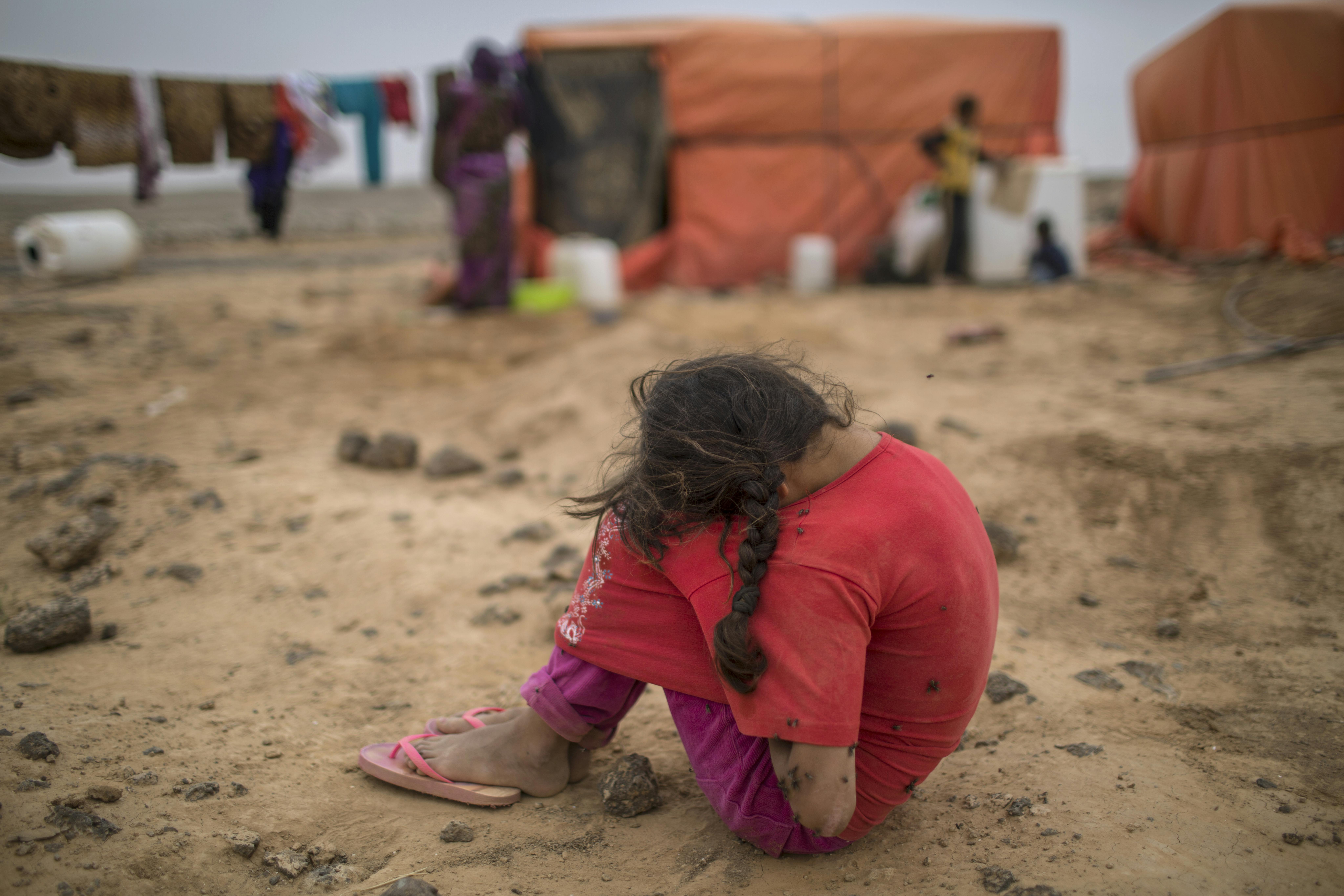 Giordania, 2018. Zahra, 7 anni, siede a terra con la testa tra le gambe. Si trova in un campo rifugiati in cui si trova con la sua famiglia da quando è stata costretta a fuggire dalla Siria