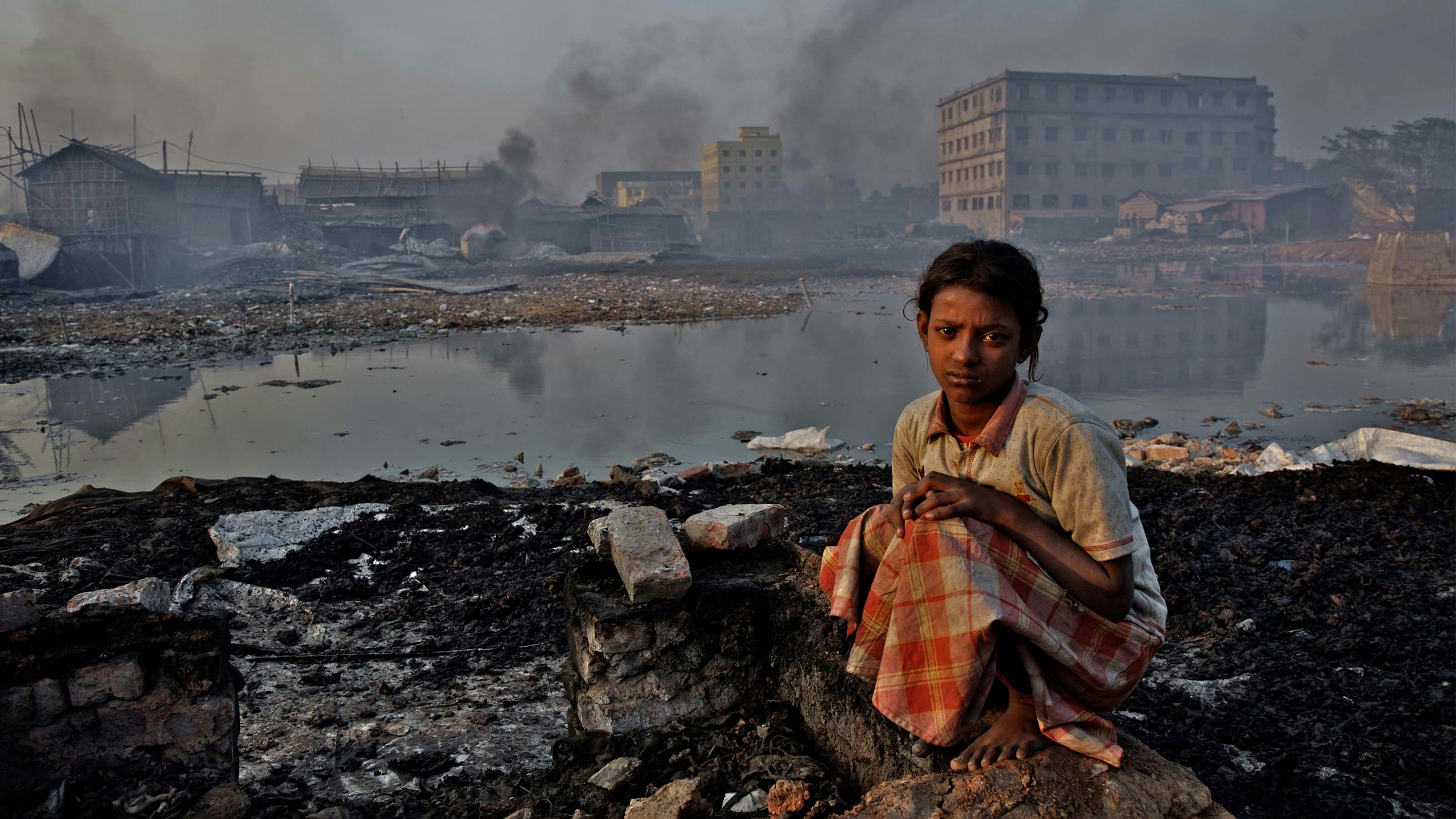Bangladesh - Una ragazza siede su un muro rotto all'interno di una fabbrica dove si lavorano le pelli di scarto per produrre colla 