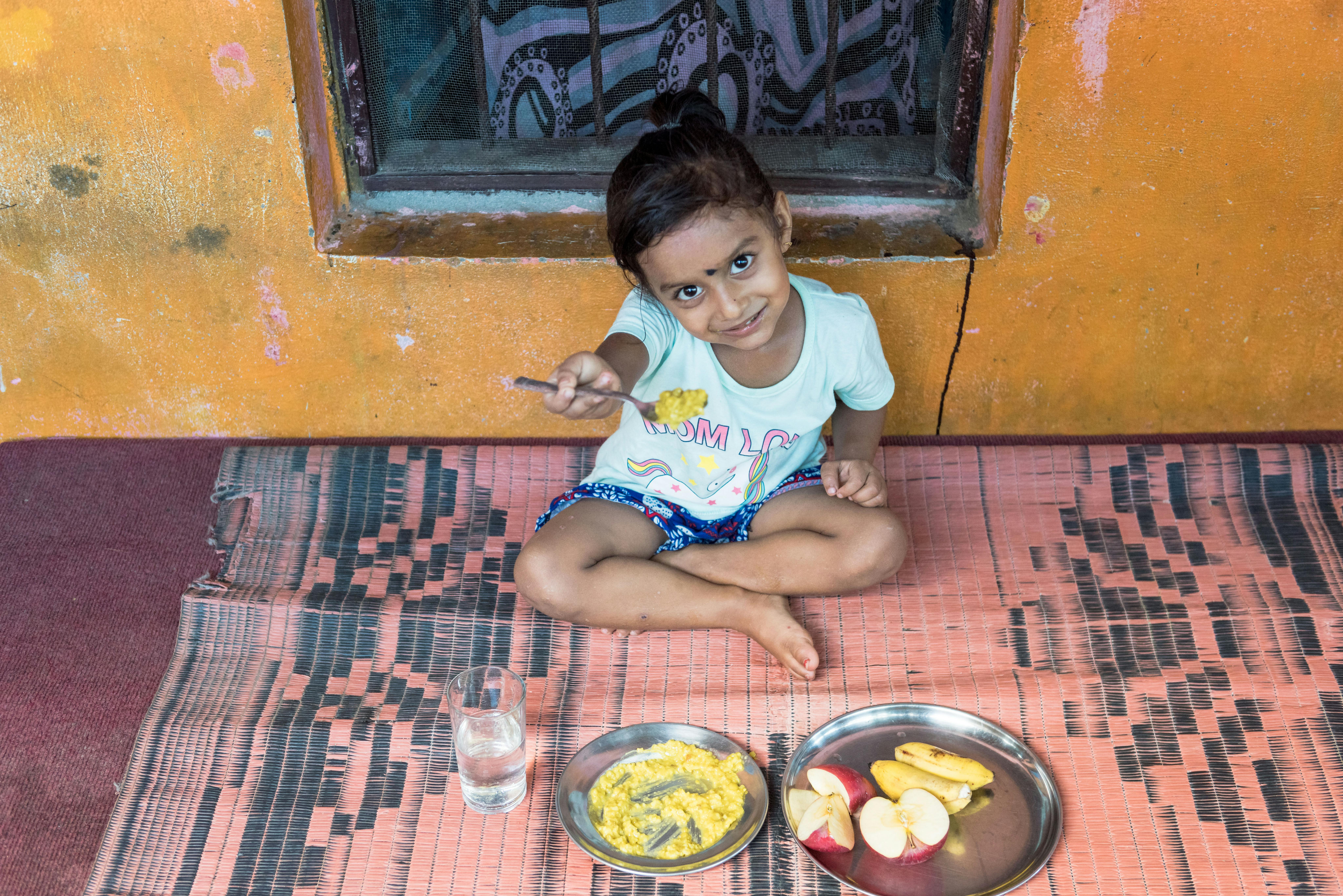 Girisha, 3 anni, ha in mano il cucchiaio con la merenda preparata dai nonni. Siamo a Ratnanagar, nel sud del Nepal.