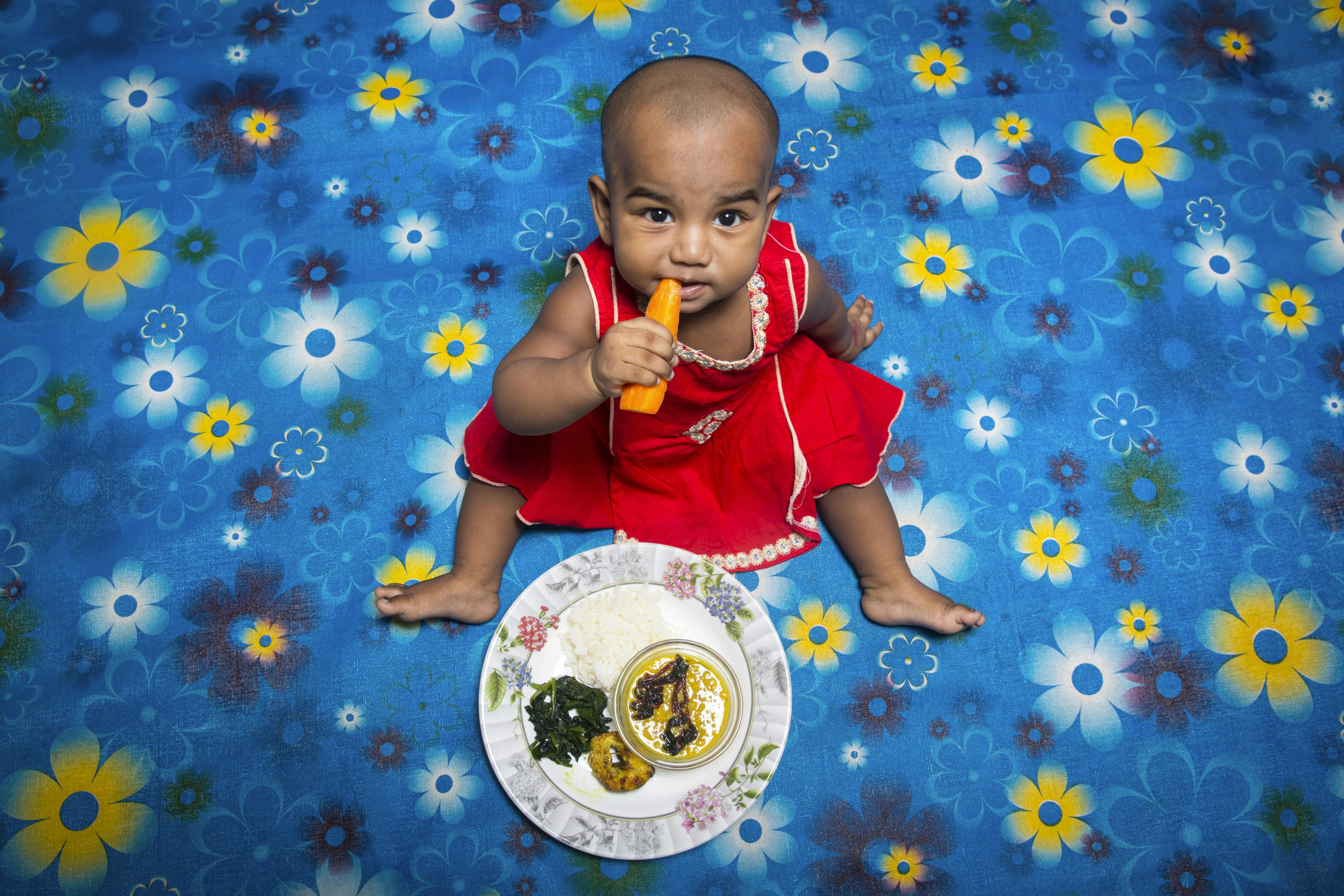 Marium, 10 mesi, sta mangiando una carota. Siamo a Dacca, in Bangladesh. 
