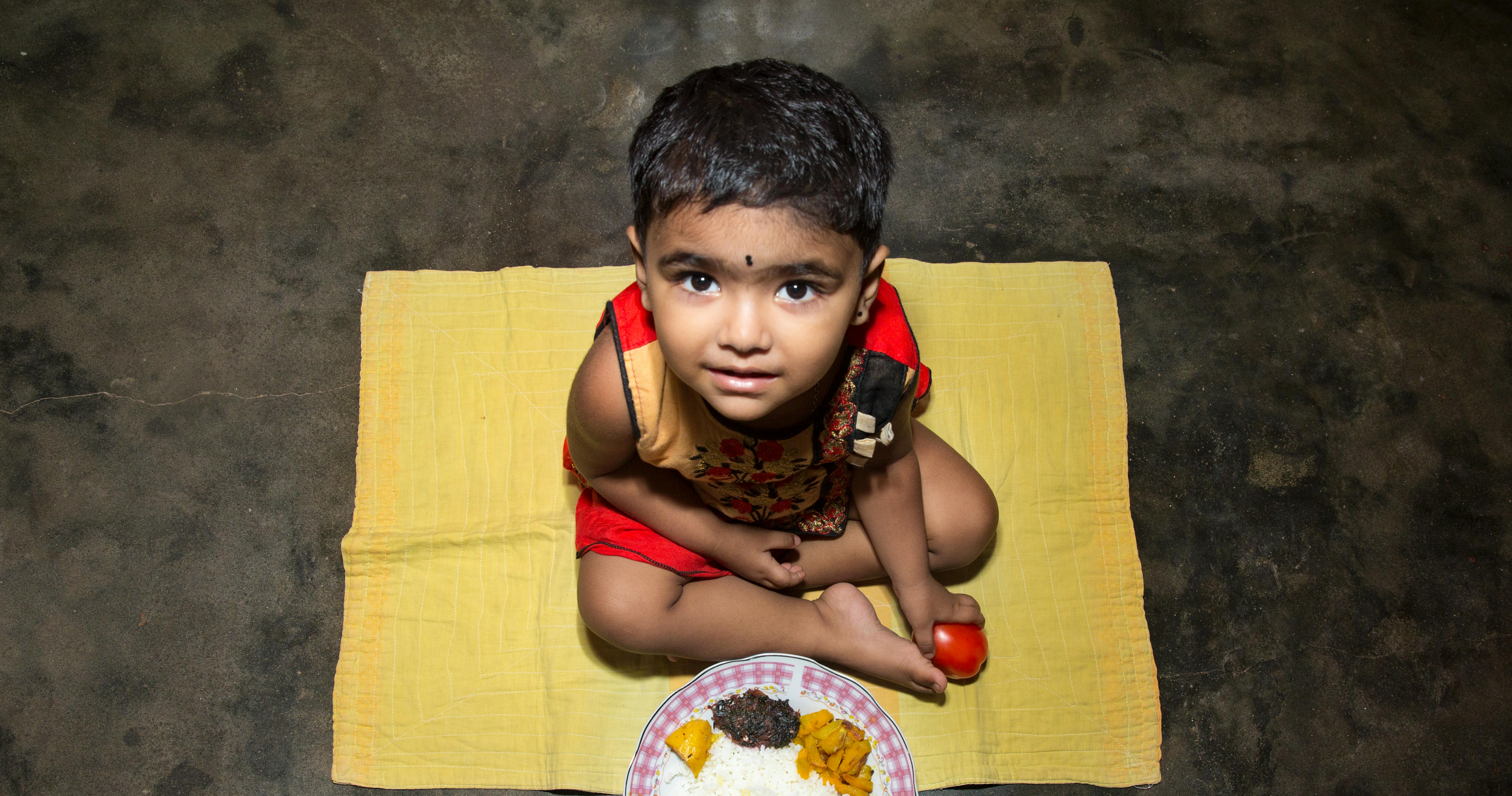 Samira, 23 mesi, è seduta di fronte alla ciotola con il suo pranzo. Siamo a Dhaka, Bangladesh