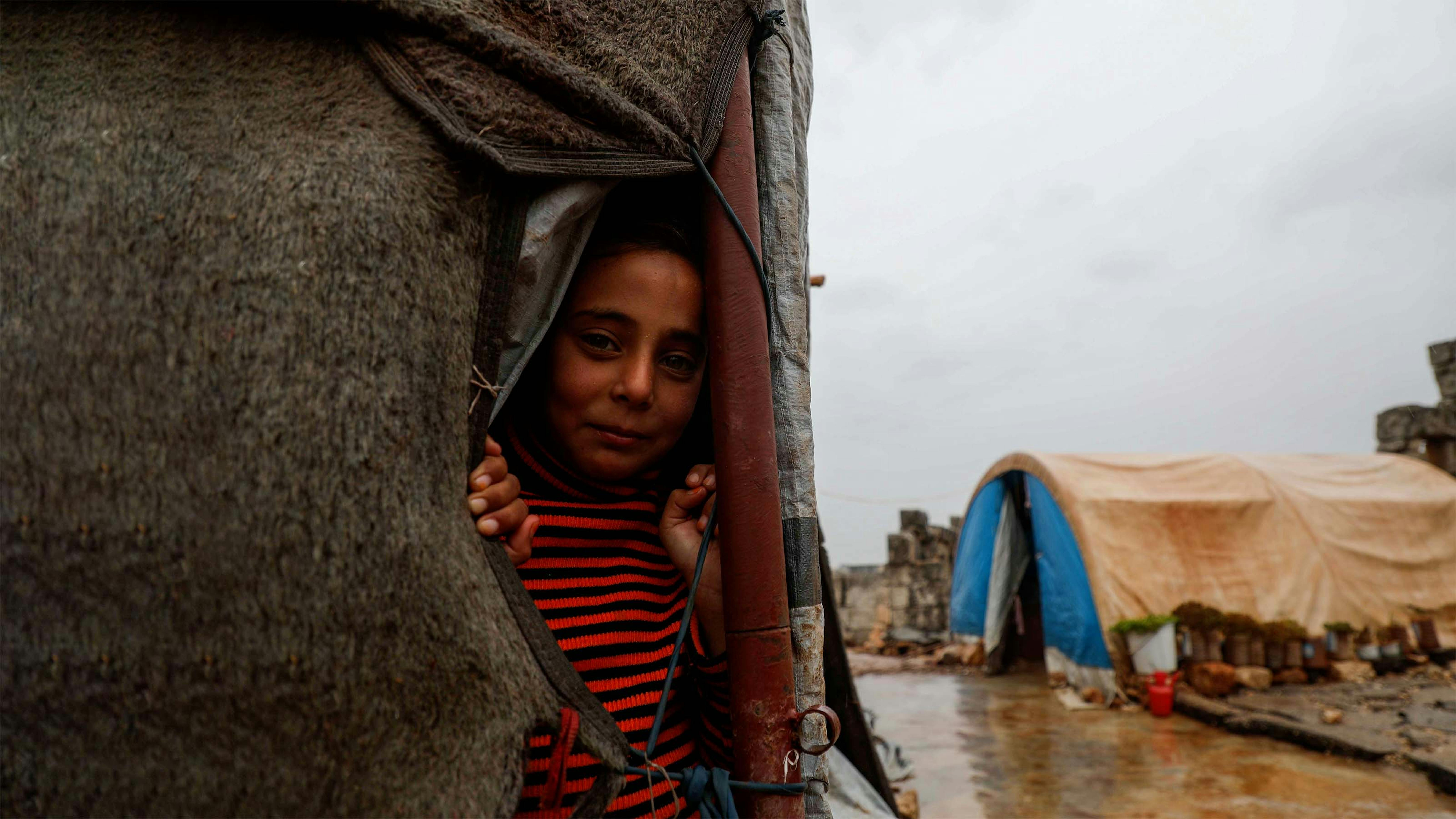 Siria, un bambino fa capolino da una tenda nel campo di Baqirha non lontano dal confine turco