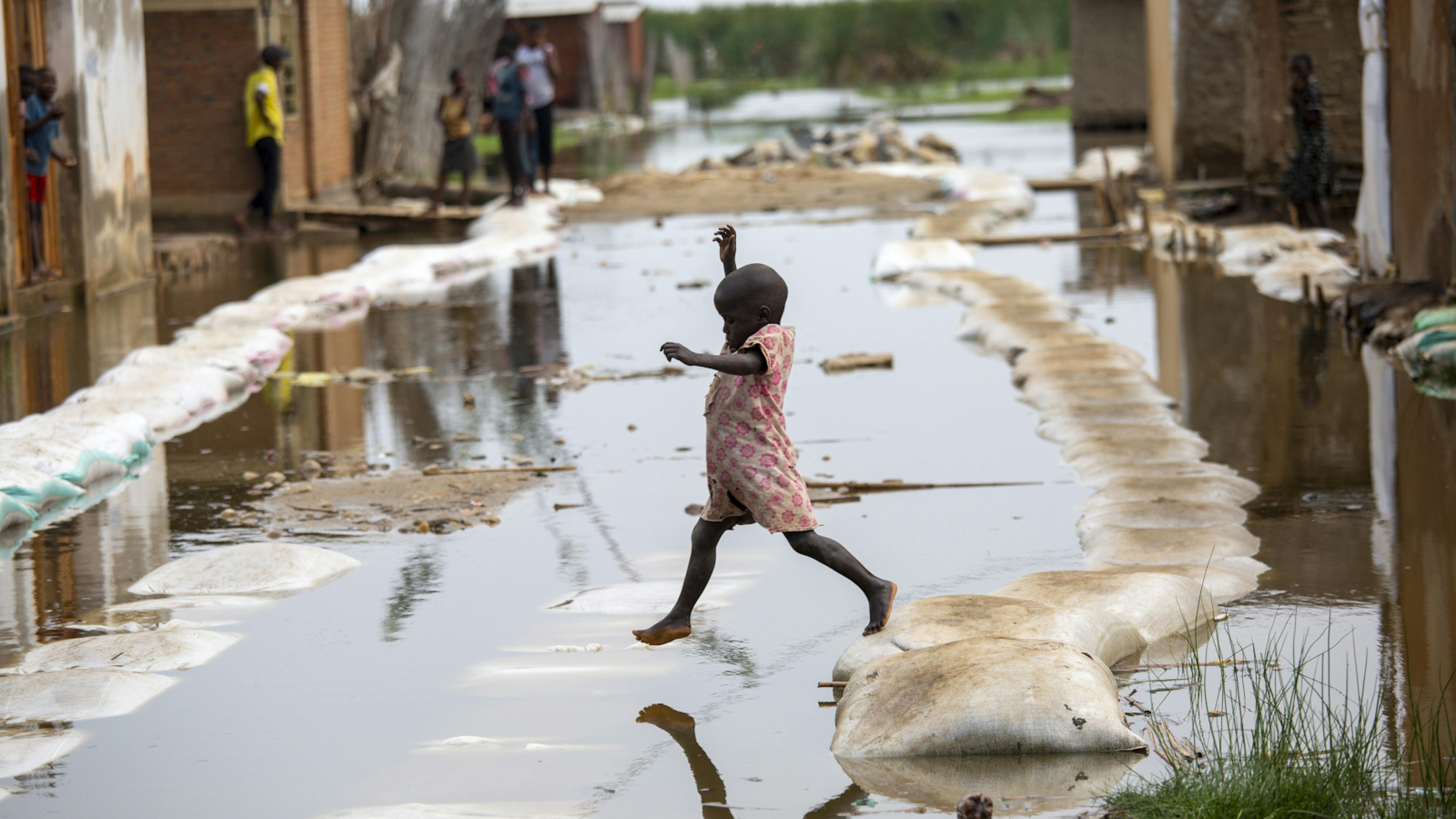 un bambino attraversa le acque alluvionali di Gatumba, 