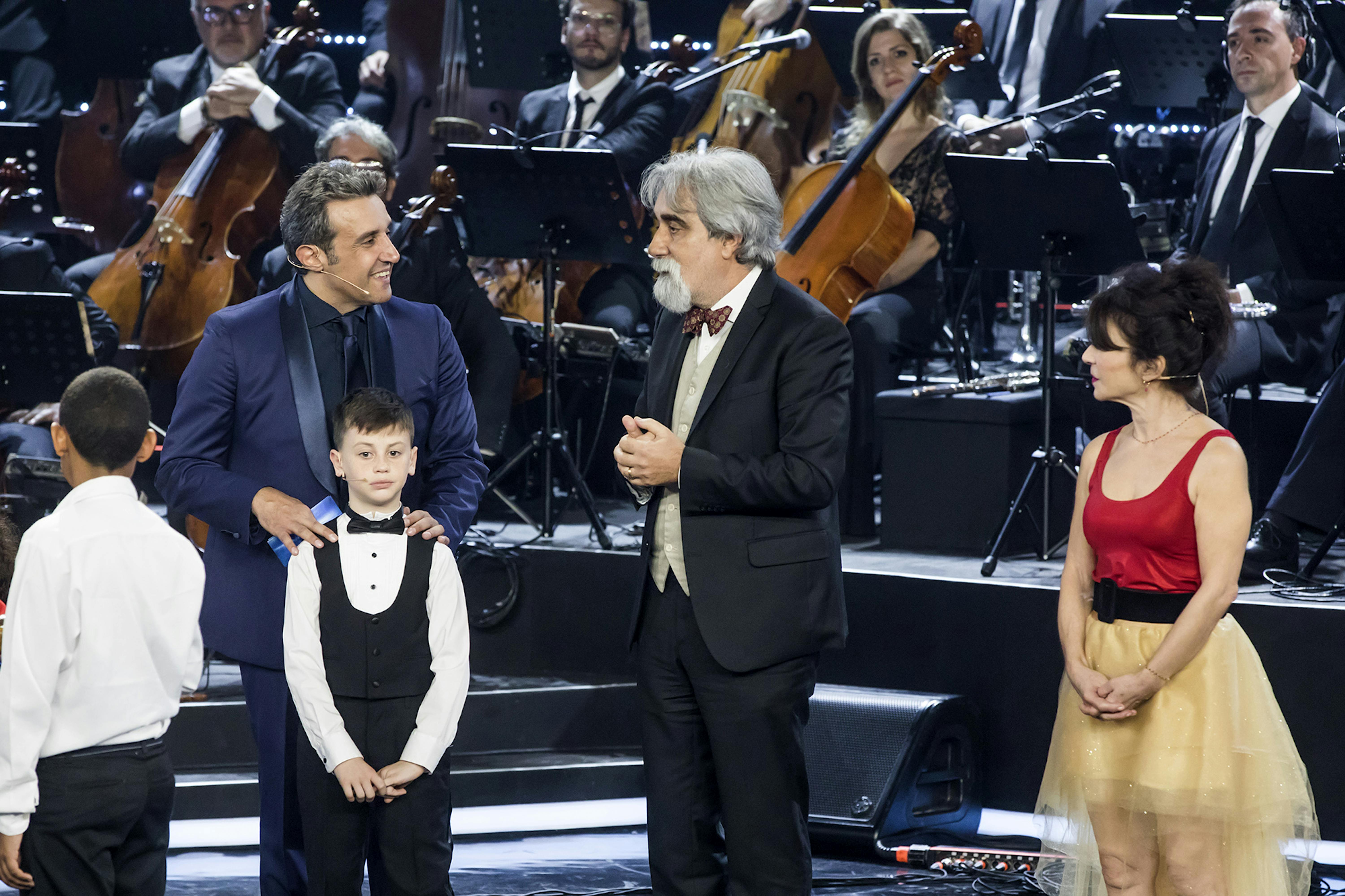 I conduttori Flavio Insinna, Natalie Guetta e Daniele Muzio , piccolo prodigio dello scorso anno, parlano con Peppe Vessicchio della recente missione con UNICEF in Venezuela