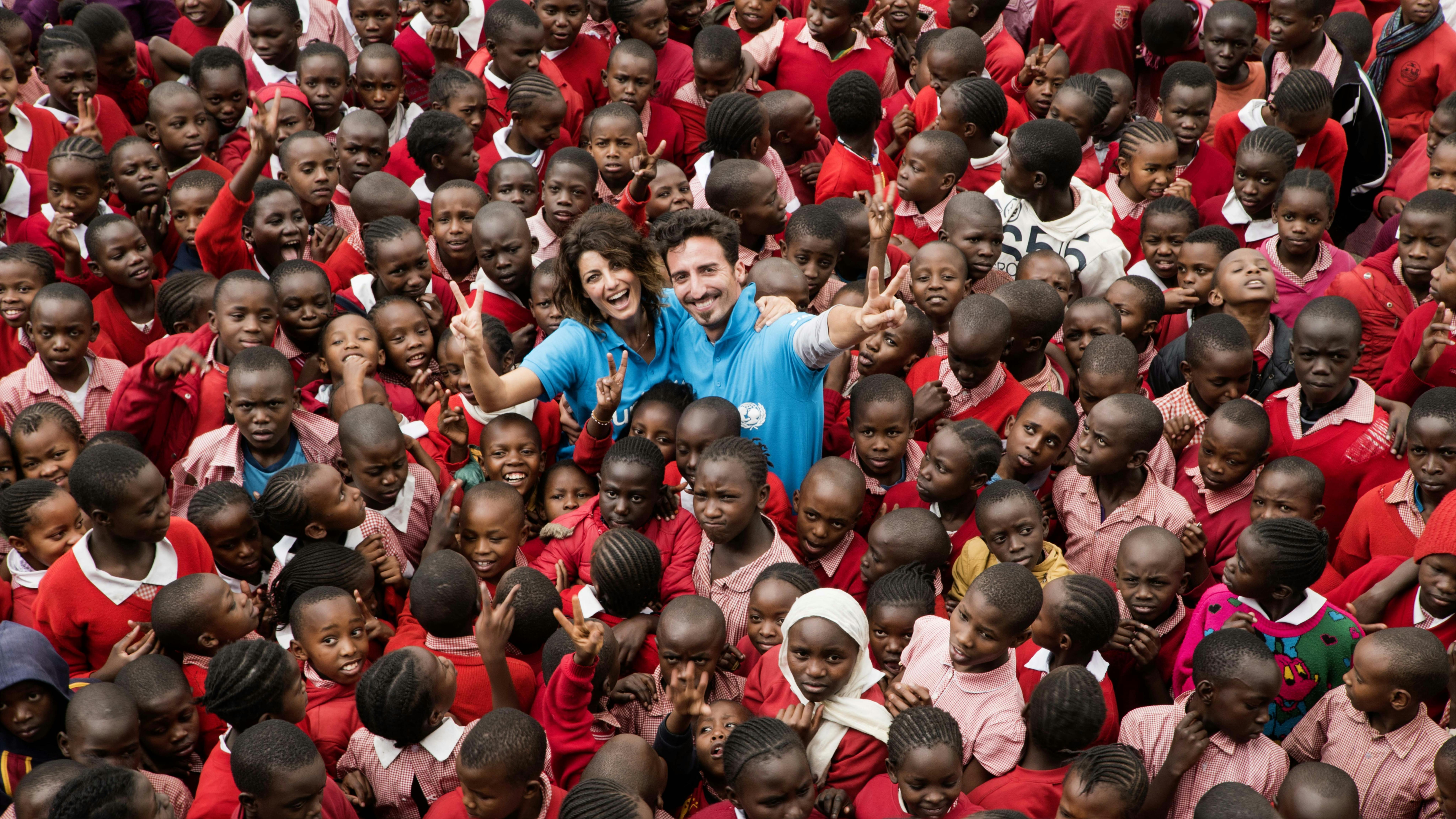 Samantha Togni e Samuel Peron sorridono mentre sono circondati da decine di bambini, siamo in Kenya