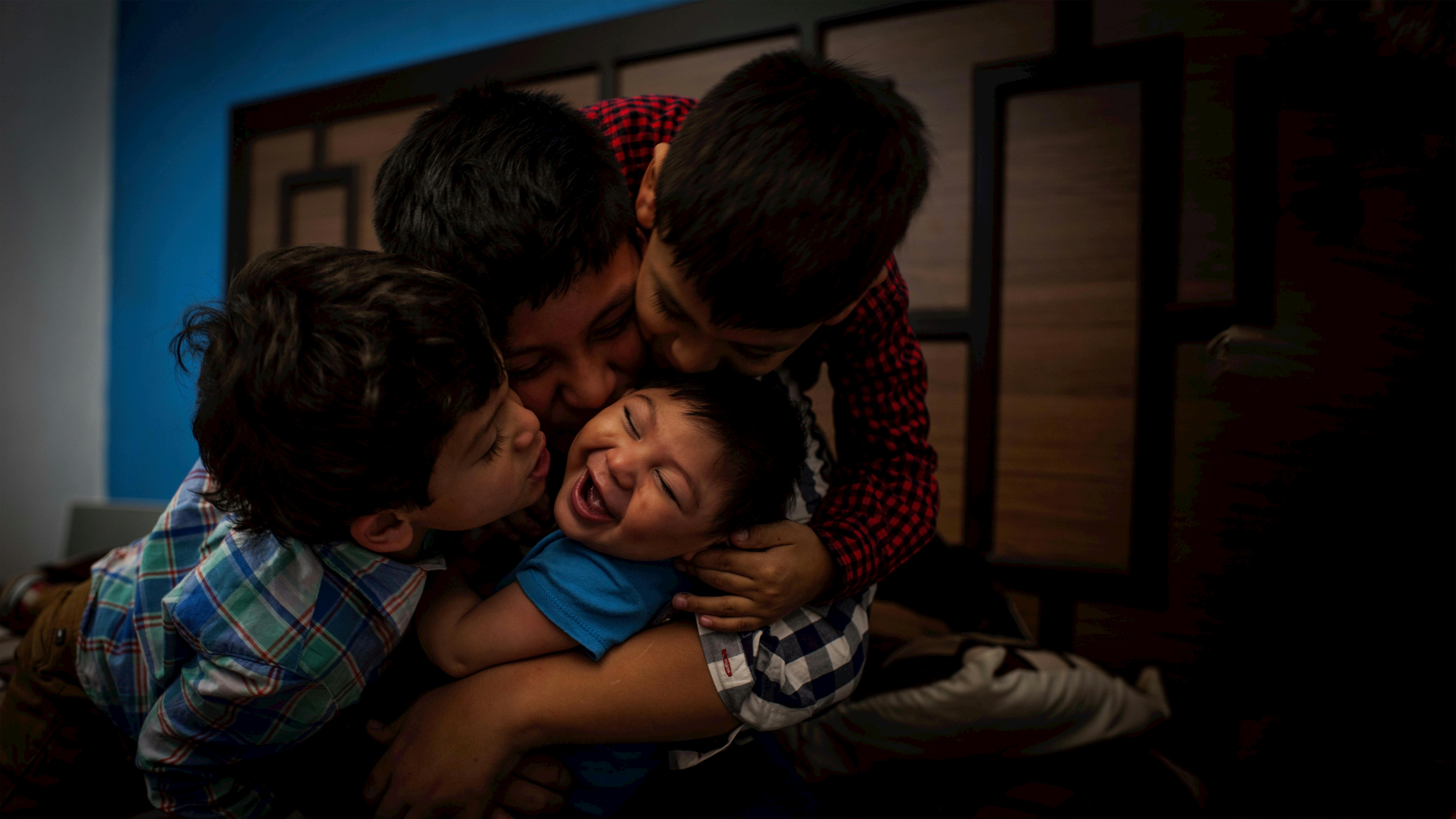 Guatemala, Danilo, un bambino disabile  di 9 mesi, riceve baci e abbracci dai suoi fratelli all'interno della loro casa