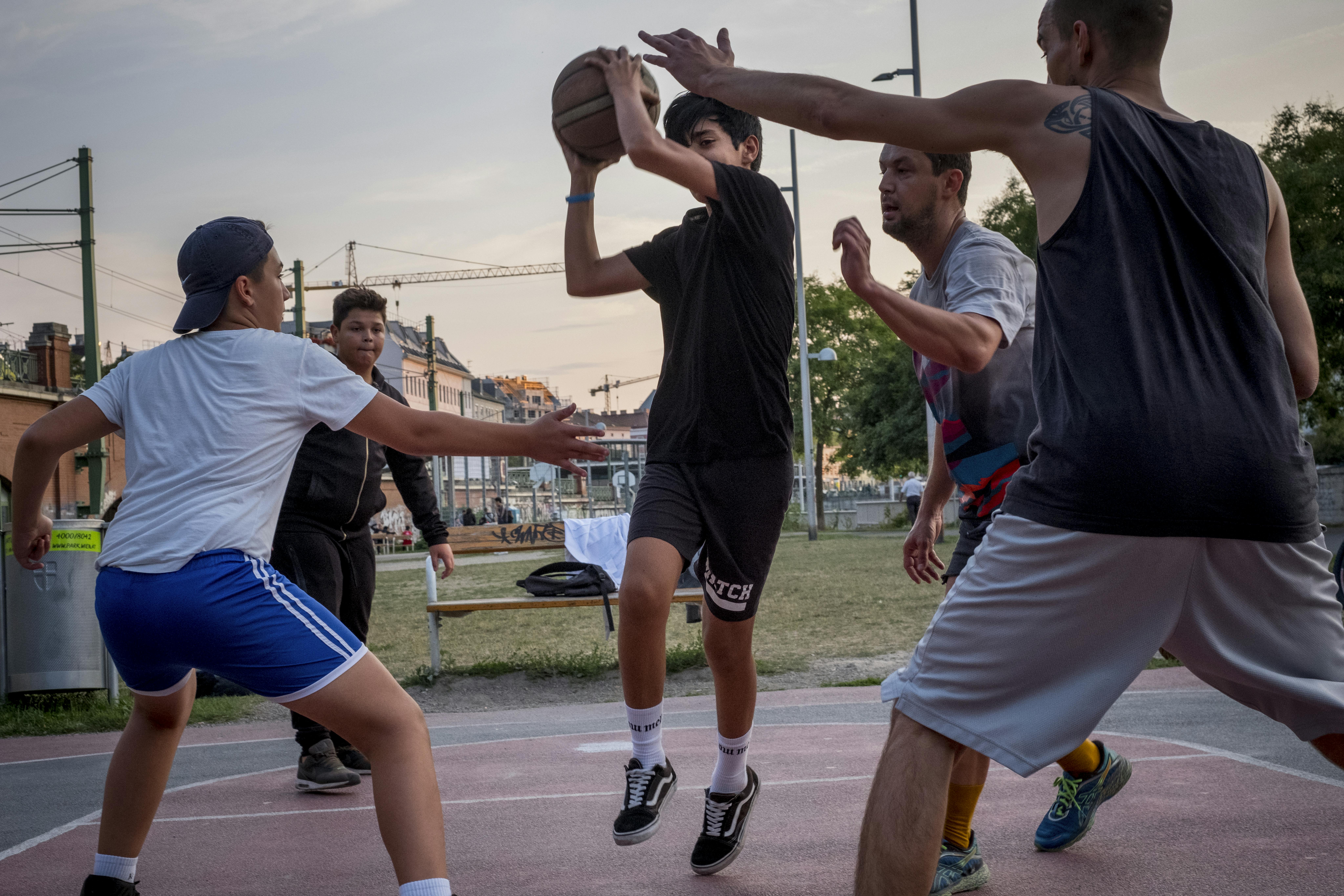 Zein al-Faraji, 14 anni, gioca a basket improvvisato con compagni austriaci che ha appena incontrato in un campo da basket nel centro di Vienna, Austria