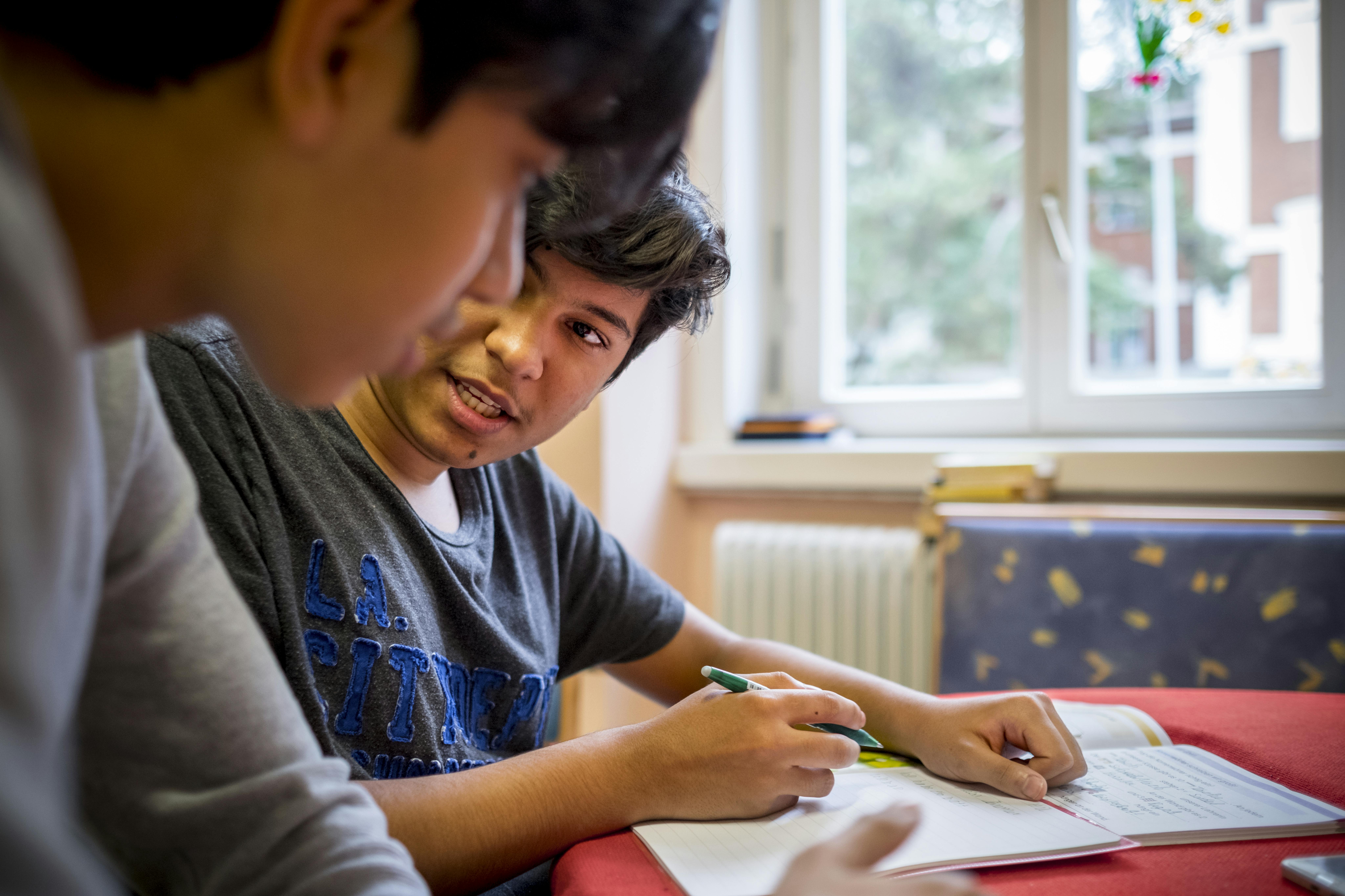 Sajad Al-Faraji, 16 anni, riceve aiuto da suo fratello Zein, 14 anni, con i suoi compiti di tedesco nella loro stanza in un ospedale per anziani abbandonato nel centro di Vienna, Austria