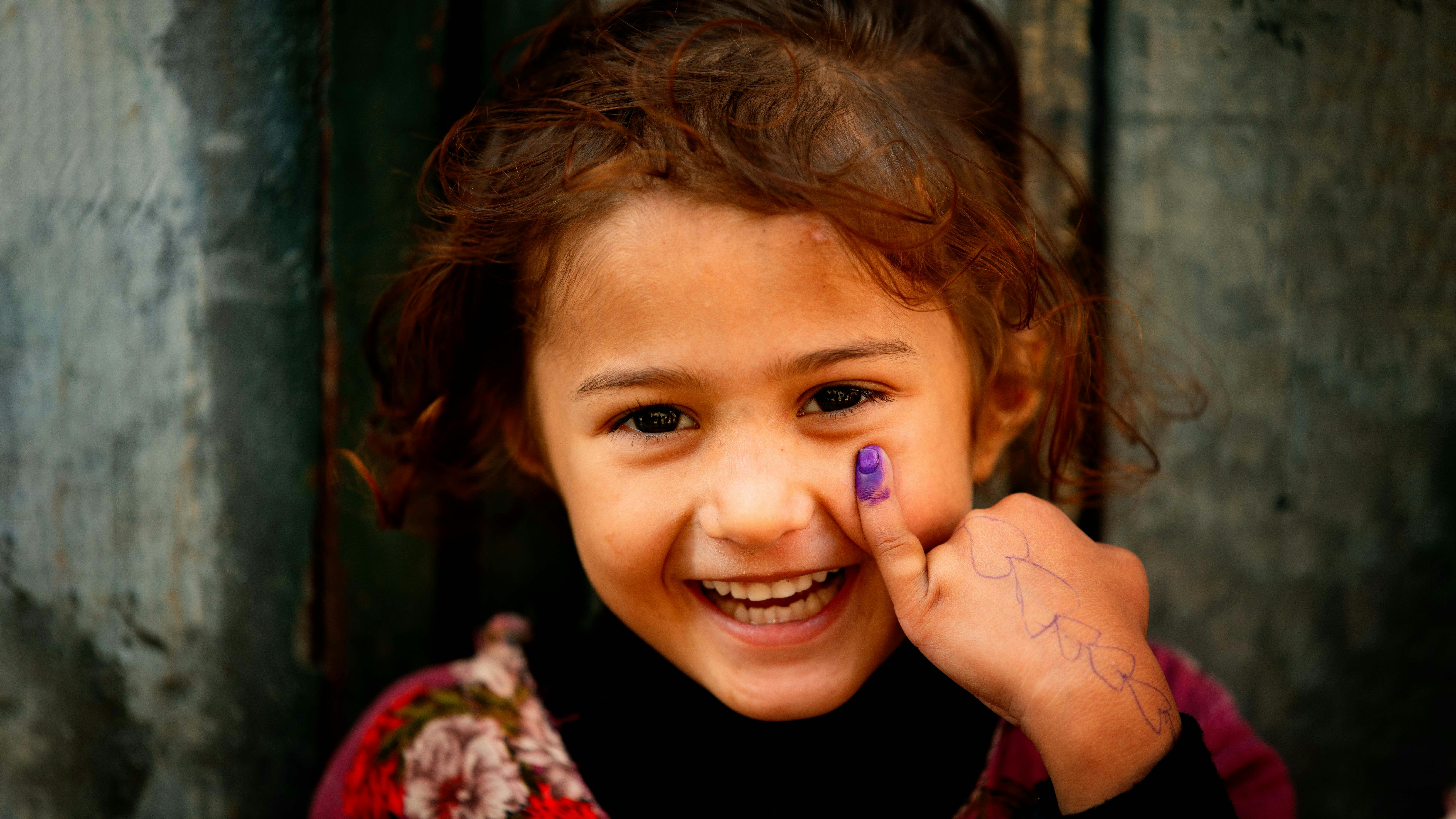 Lahore, una bambina di quattro anni sorride e mostra il dito segnato dopo aver ricevuto il vaccino contro la poliomielite