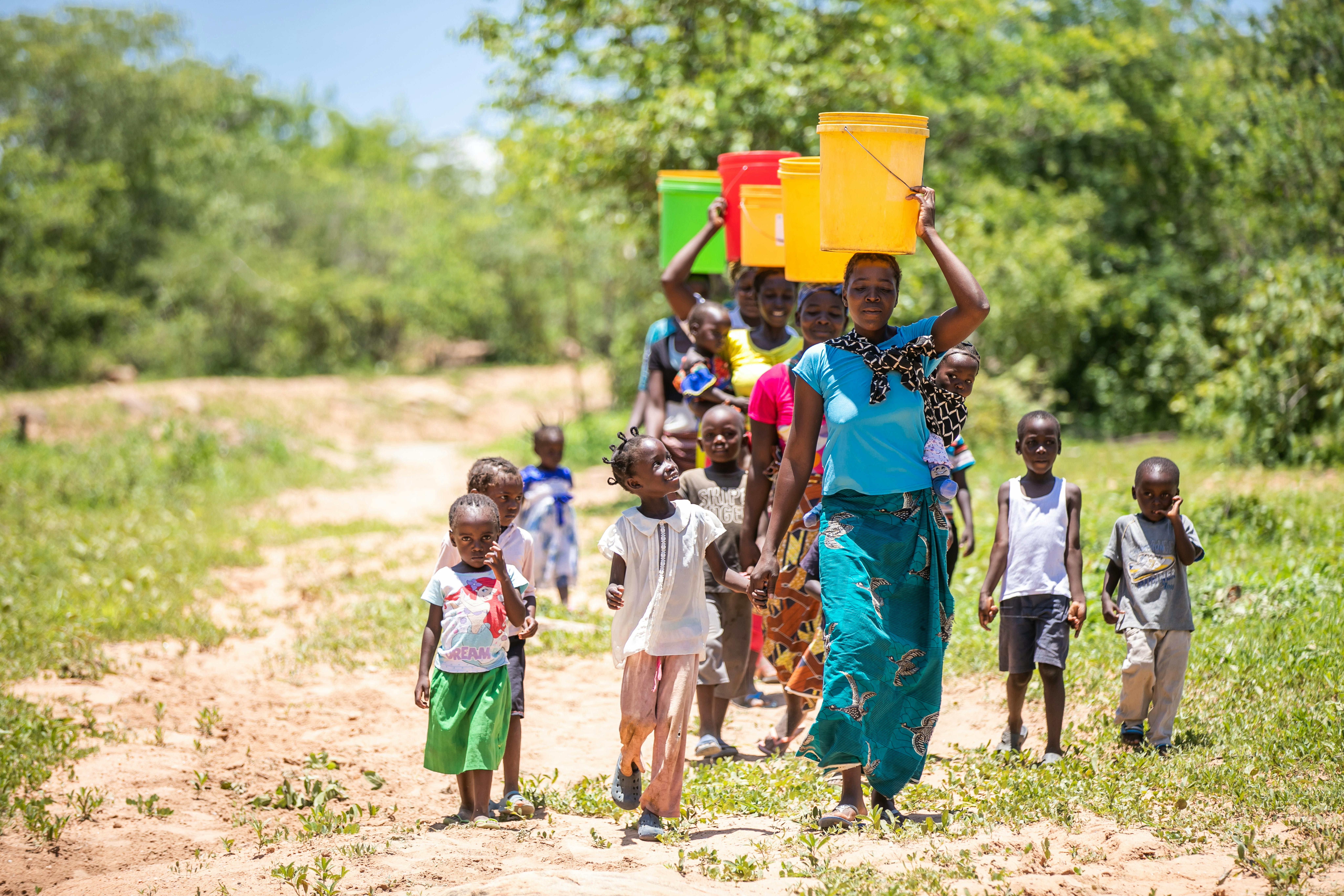 Donne e bambini camminano insieme per raccogliere l’acqua da un pozzo, nella Valle di Gwembe, in Zambia. 