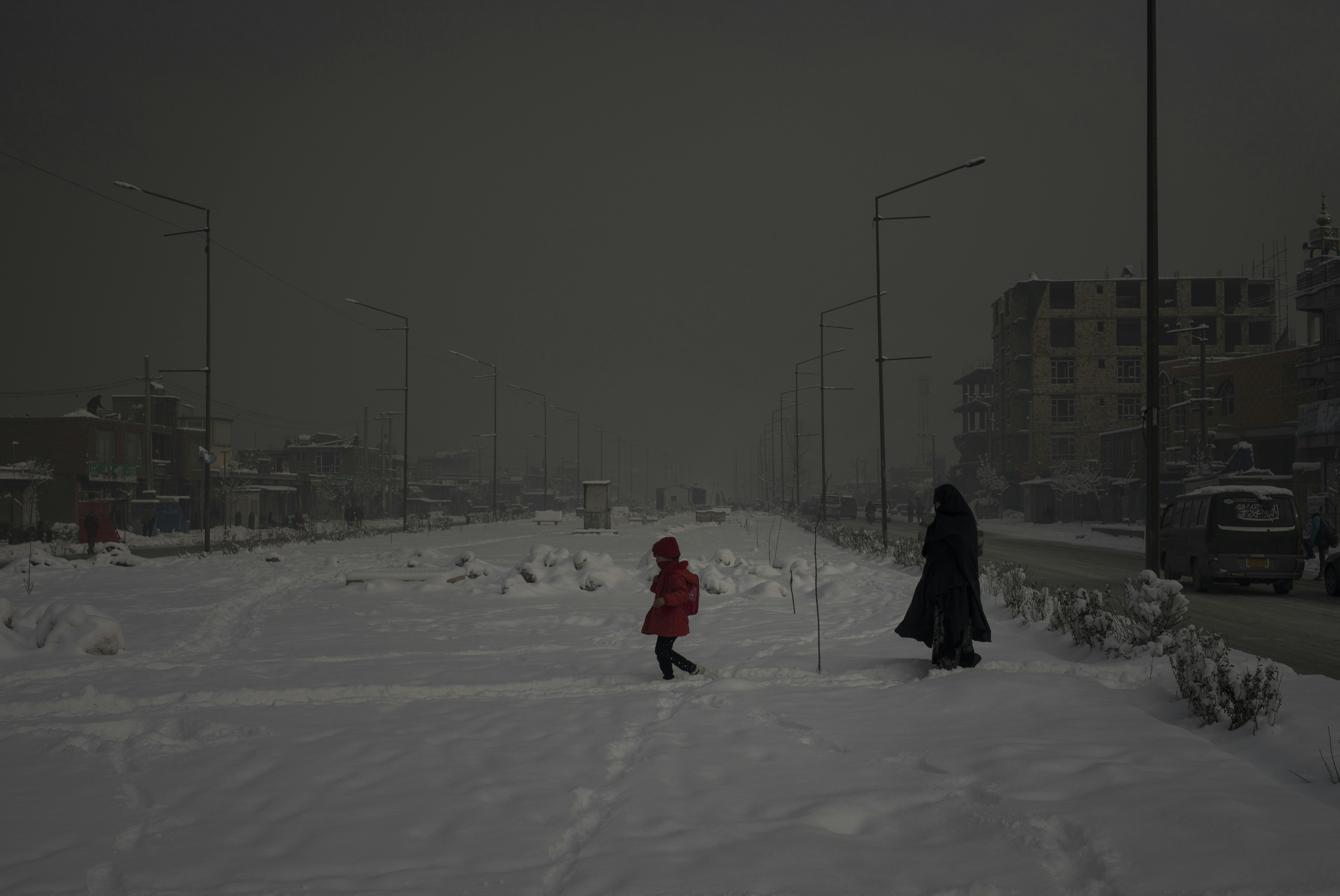 In una mattinata particolarmente inquinata, una mamma cammina con sua figlia attraverso un’area coperta della neve a Kabul, in Afghanistan. 
