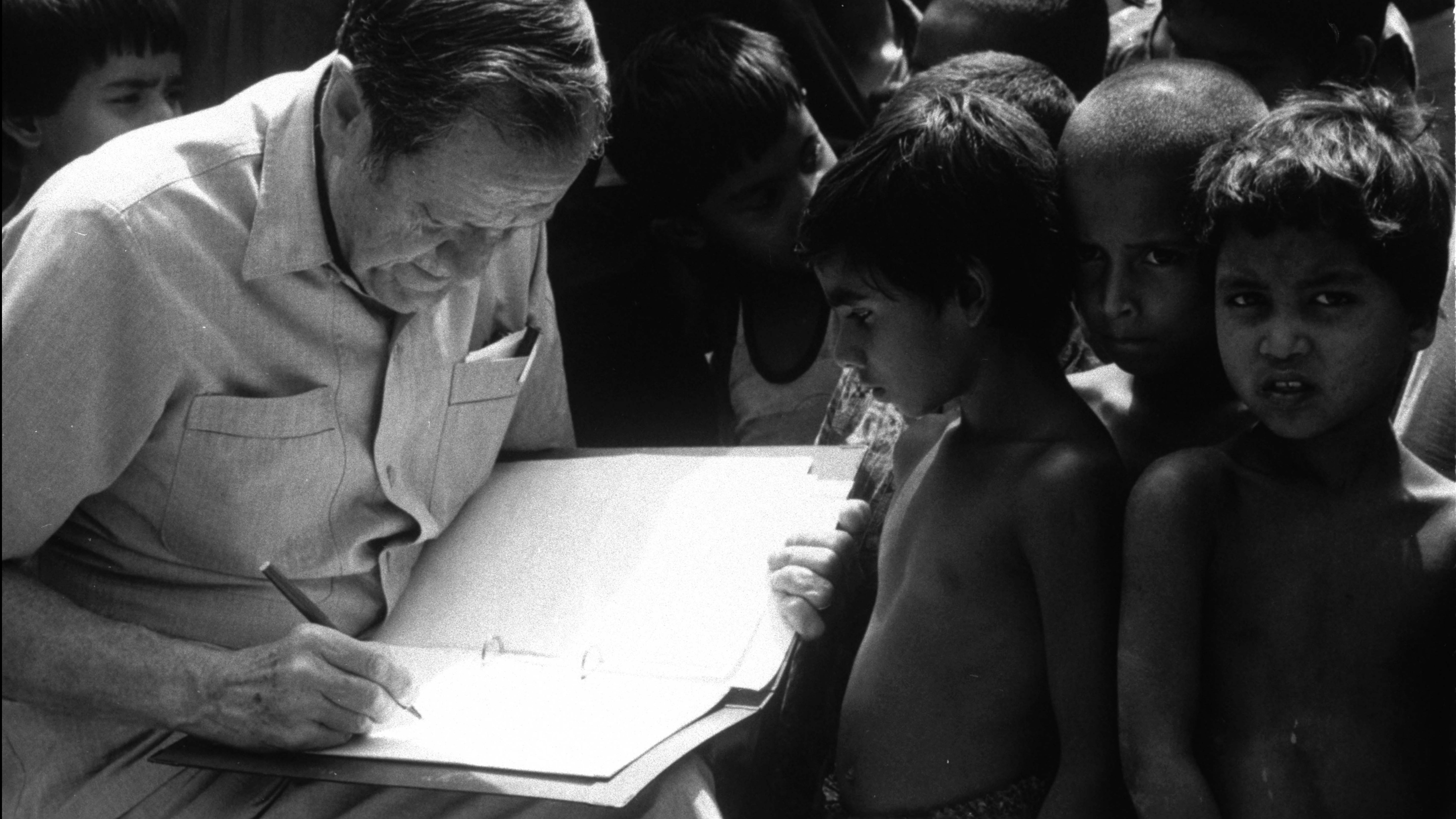 Bangladesh, I bambini guardano mentre il direttore dell'UNICEF James Grant firma un documento