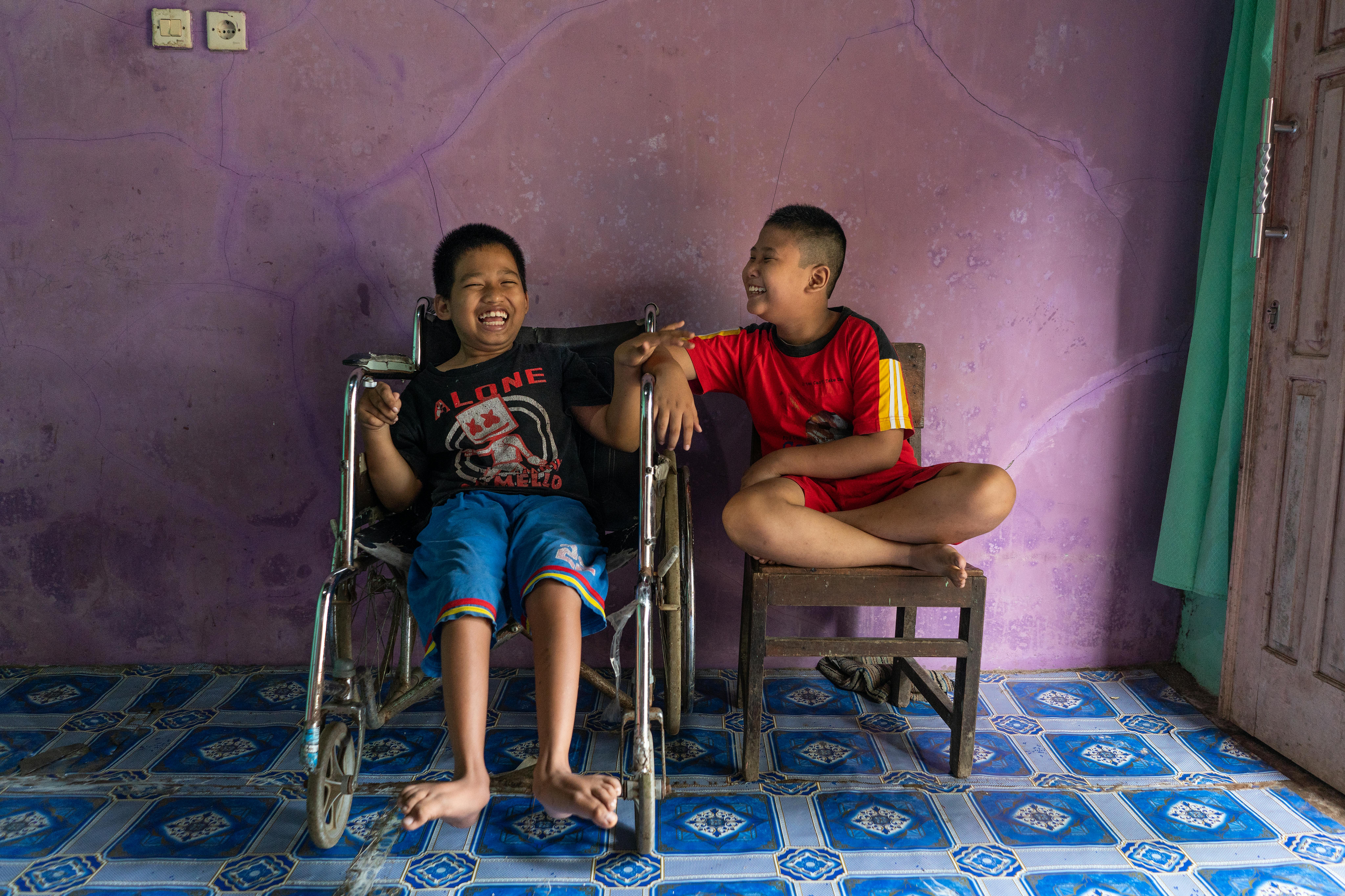 Syaiful, 12 anni, è un bambino con disabilità fisica;  è seduto accanto al suo amico Kevin Saputra, 9 anni, con disabilità visiva, sono nella casa di Syaiful's a Banyumas, Java Centrale, Indonesia.