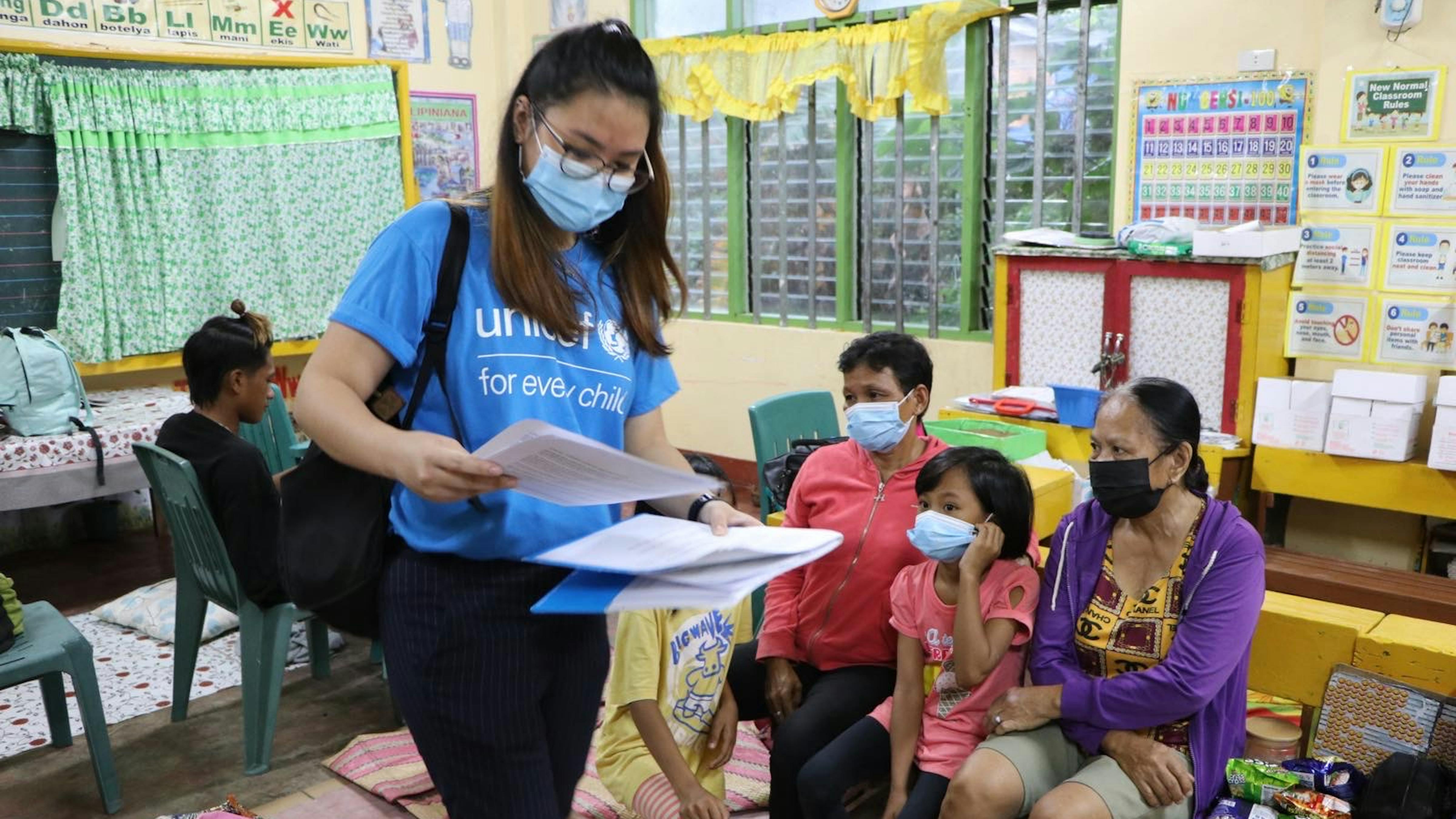 Filippine, una famiglia evacuata da una zona a rischio è assistita dallo staff UNICEF