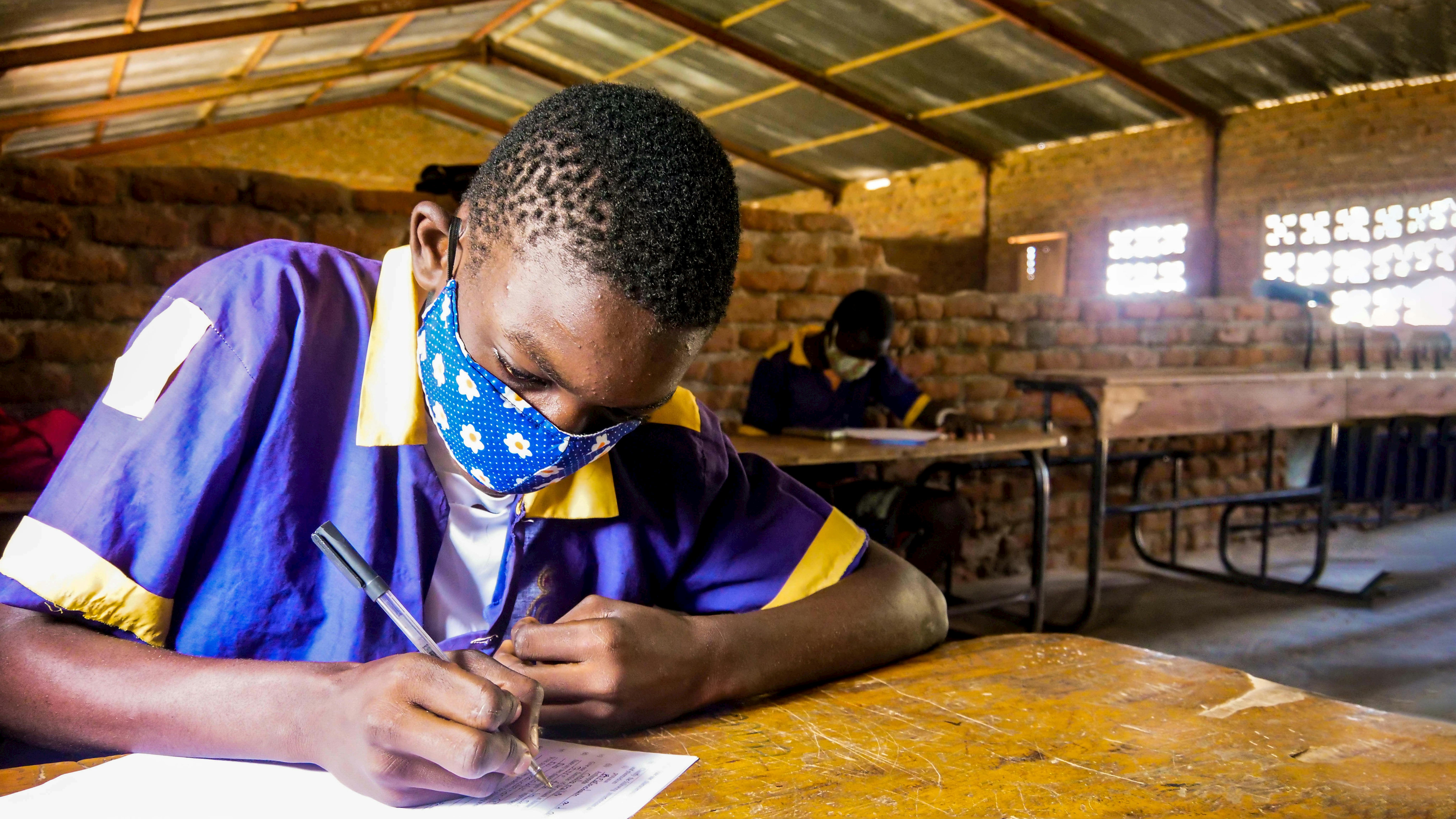 Malawi - Uno studente con la mascherina svolge il suo compito duranteuna pausa della lezione alla scuola elementare di Mchoka.