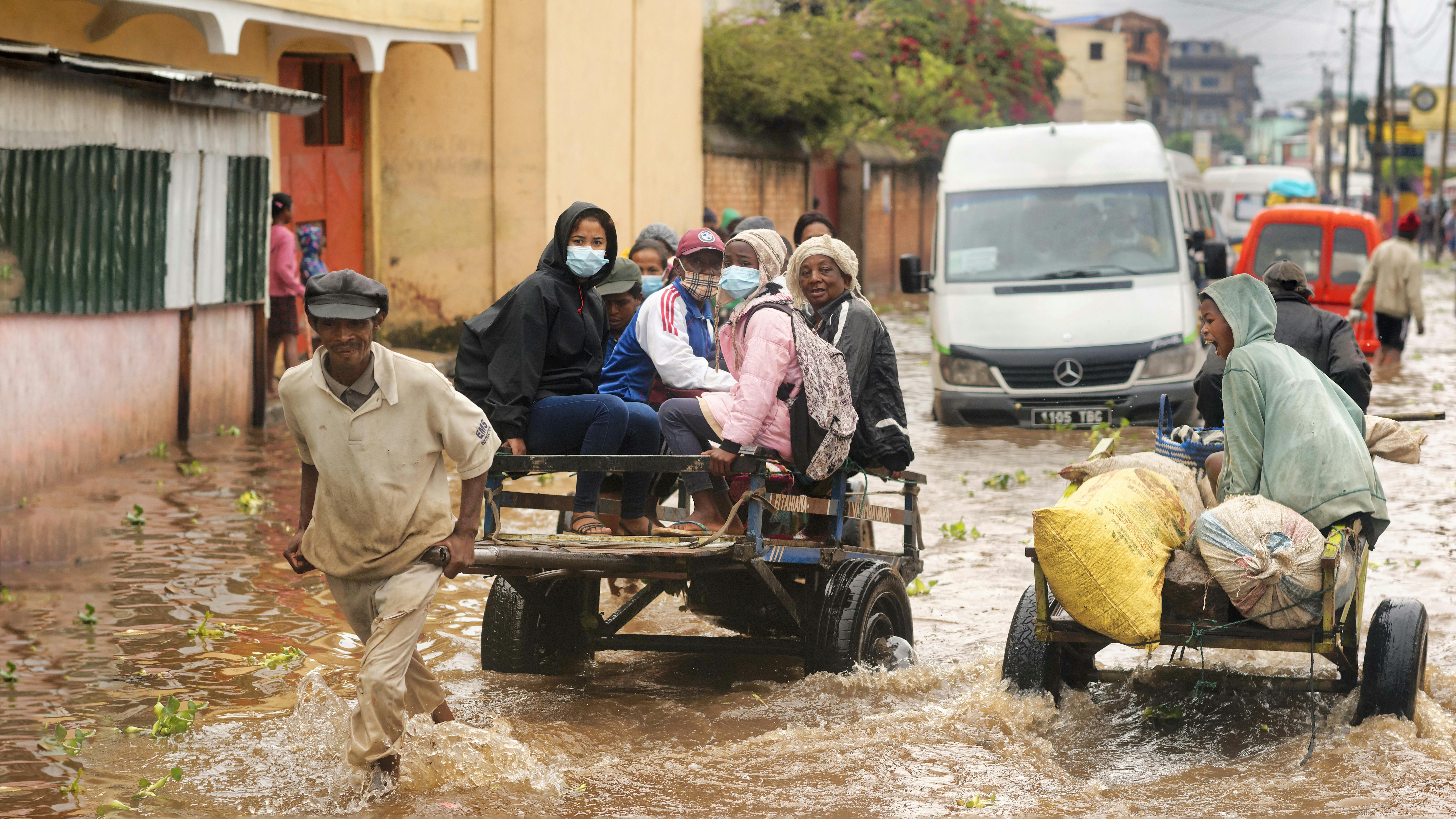 Madagascar, un gruppo di persone su un carretto attraversano strade invase dall'acqua, dopo aver pagato piccole somme di denaro per essere trasportate