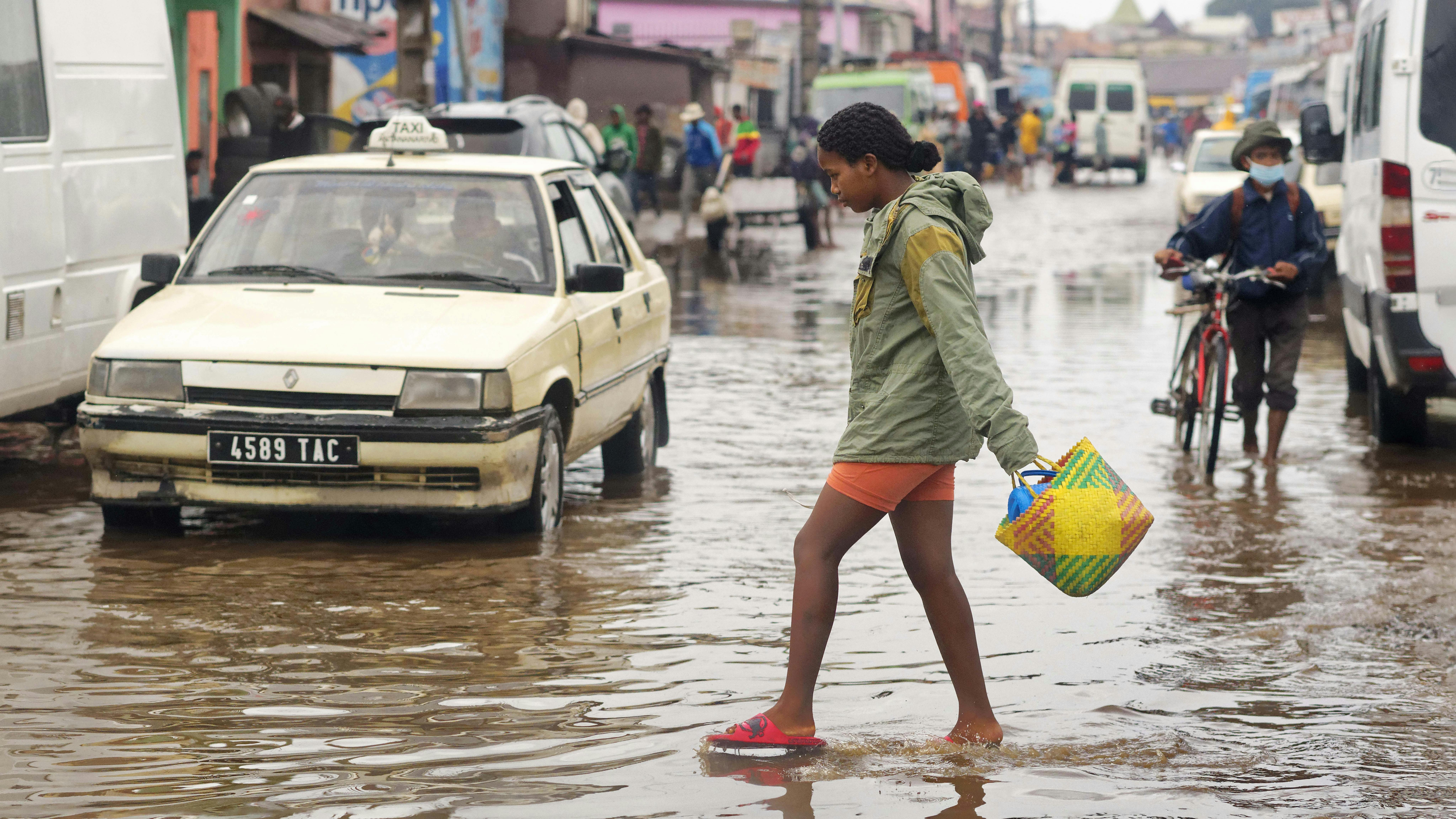 Madagascar, una giovane ragazza attraversa una strada allagata, portando dell'acqua