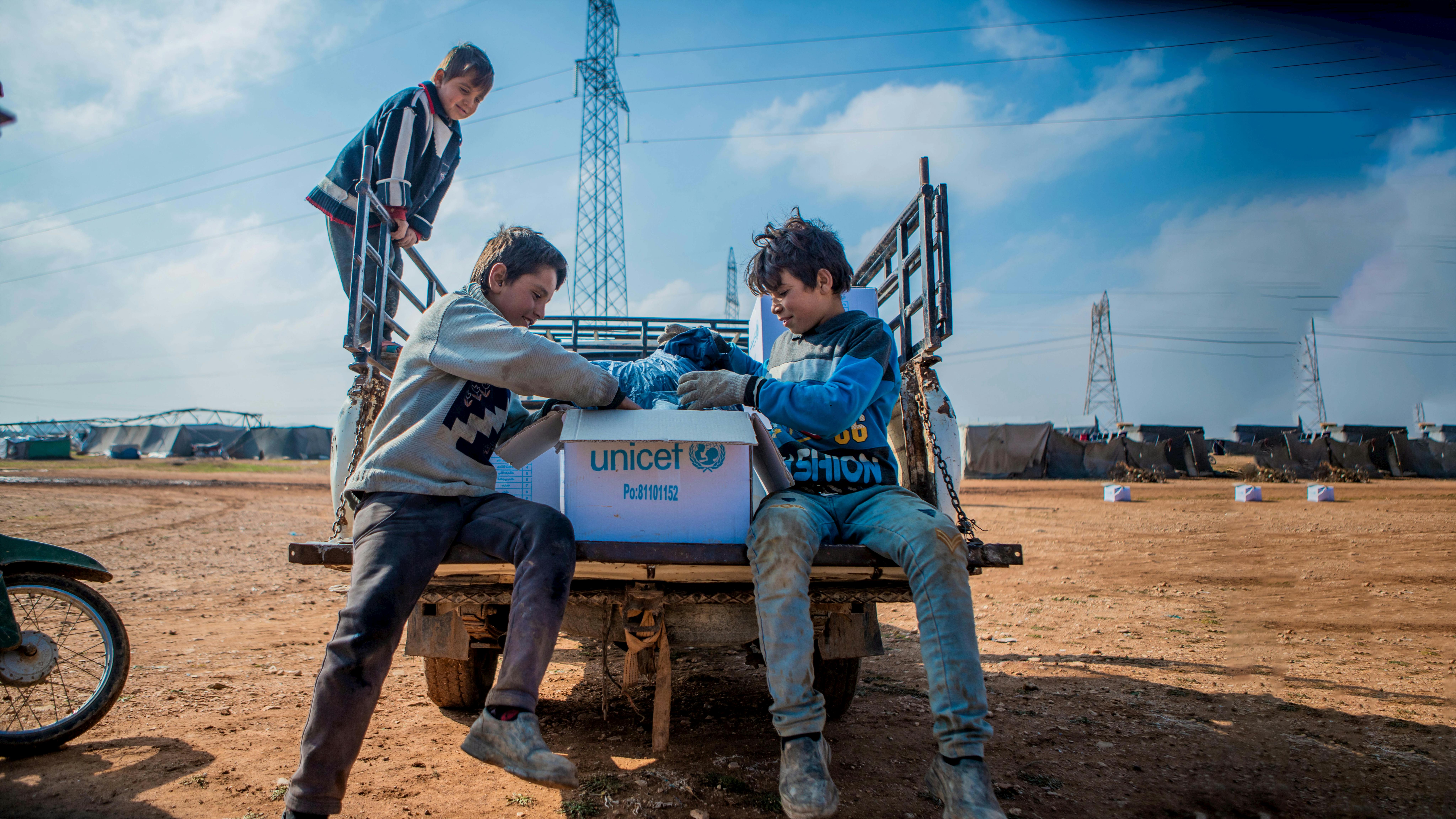Yamen, 13 anni, a sinistra, e suo fratello di 12 anni Yousef, a destra, esplorano il contenuto di un kit di abbigliamento invernale donato dall'UNICEF nel campo improvvisato di Alzhouriyeh. 