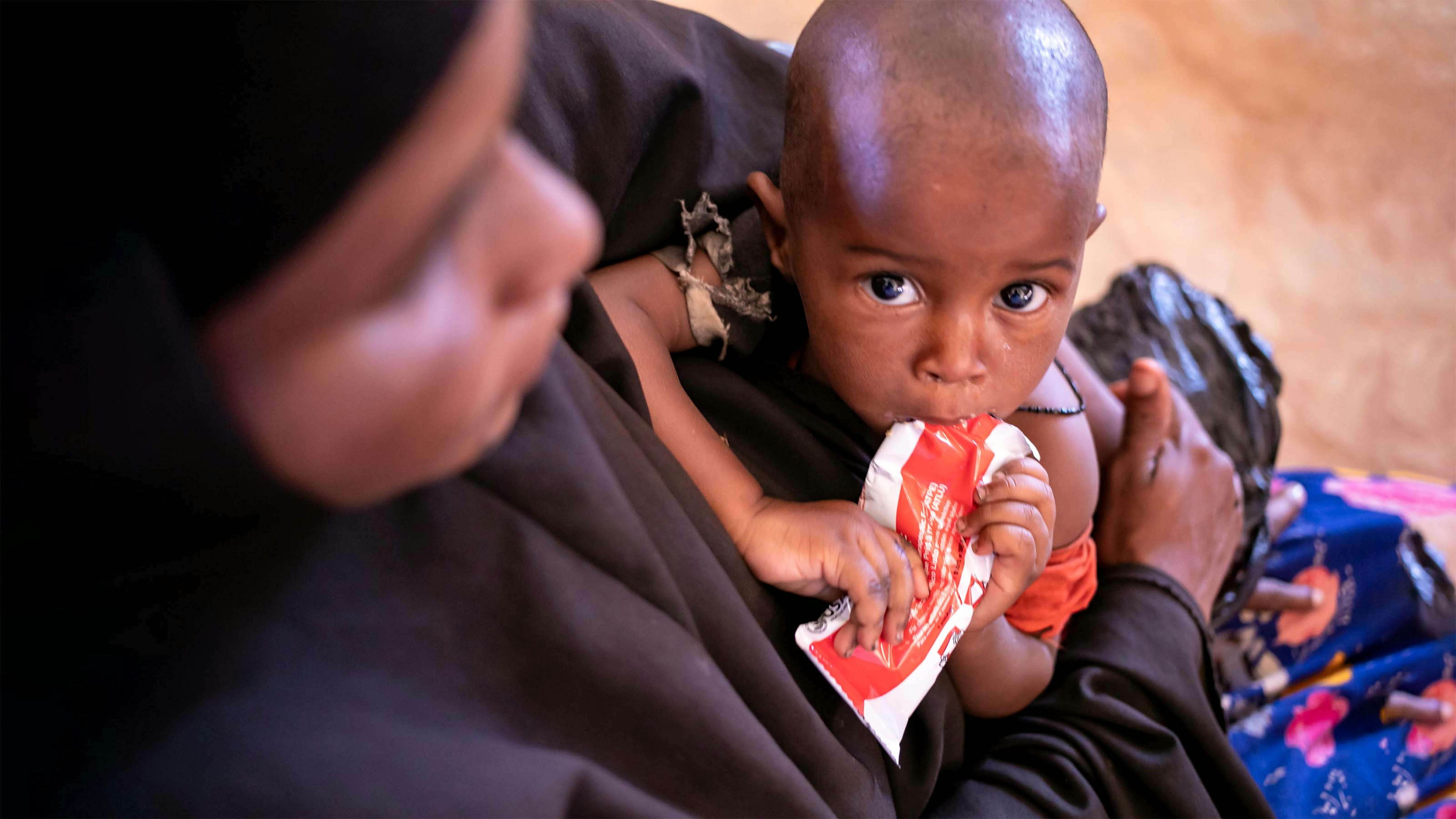 Somalia, una donna con il  suo  bambino che si nutre di un alimento terapeutico.