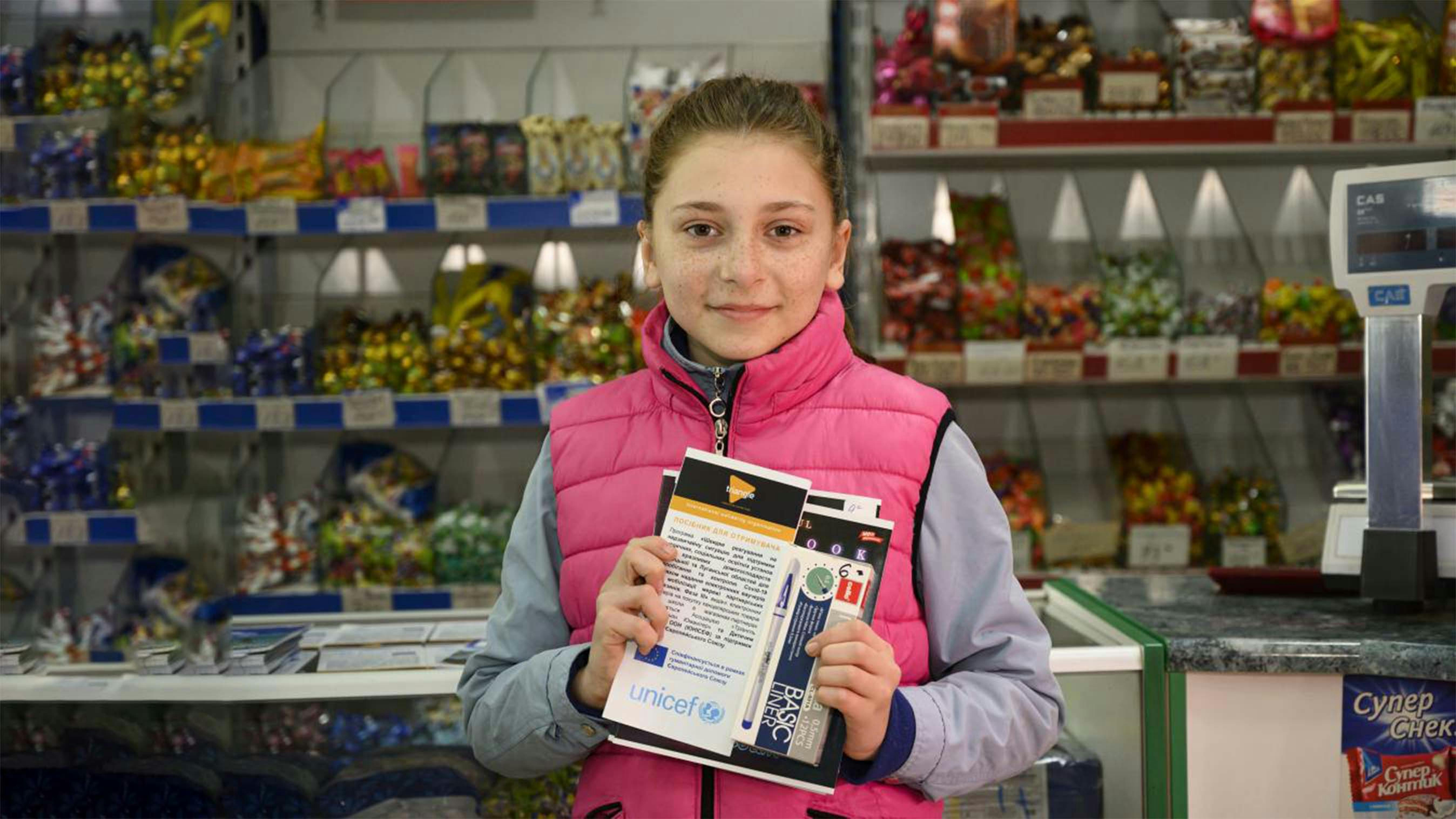 Nadia sorride mentre si riforne di materiale scolastico nella bottega del villaggio di Hranitne, a meno di un kilometro dalla linea di contatto nell’Ucraina orientale. 