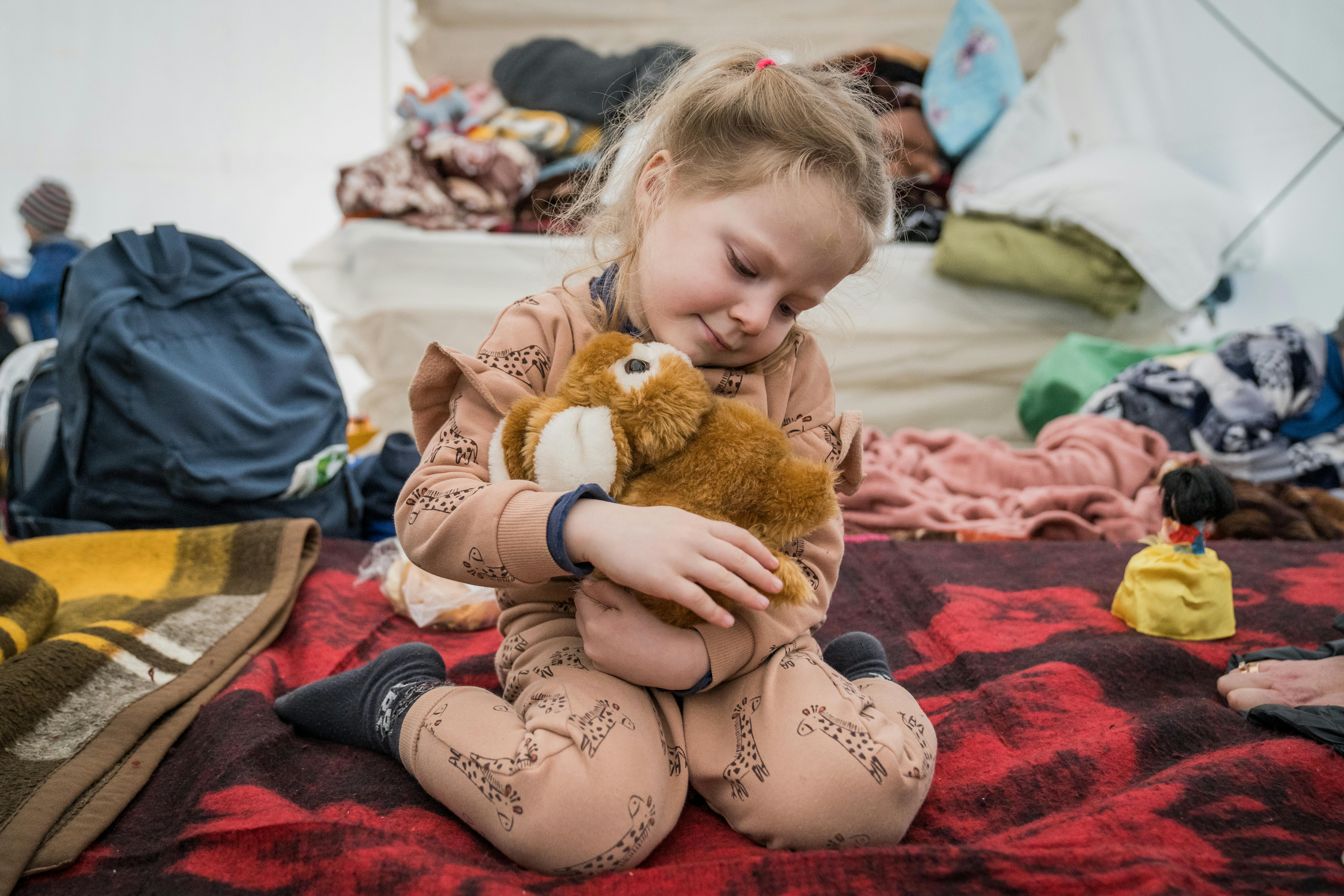 Mira, quasi 4 anni, abbraccia con gioia il suo peluche mentre si trova all'interno di una delle tende del punto di transito profughi a Isaccea, al confine con la Romania
