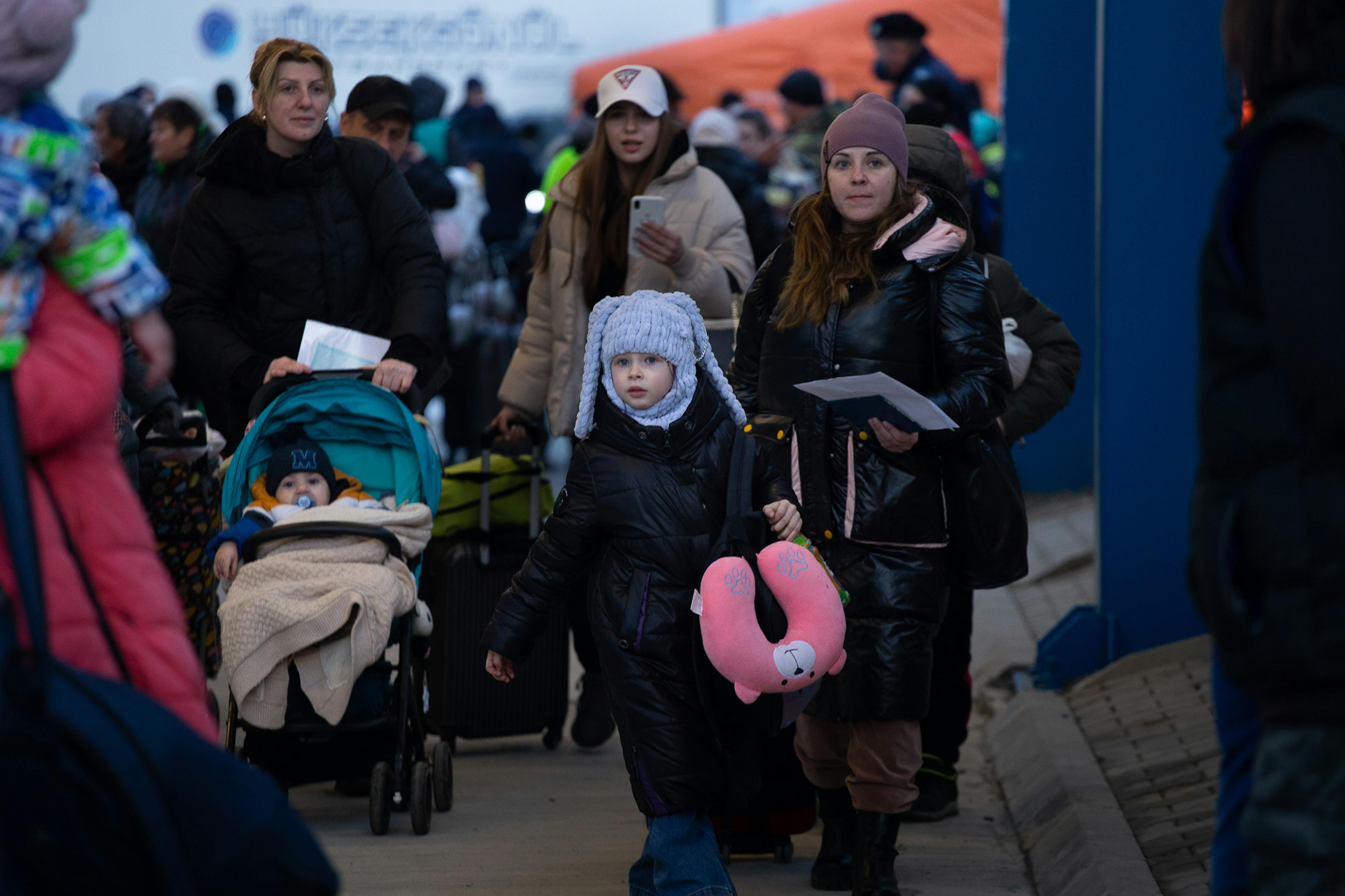 Cxusha, 9 anni, e sua madre Iulia stanno cercando di vedere cosa li aspetta dopo il punto di controllo passaporti a Isaccea, in Romania. Dietro di loro altre decine di profughi