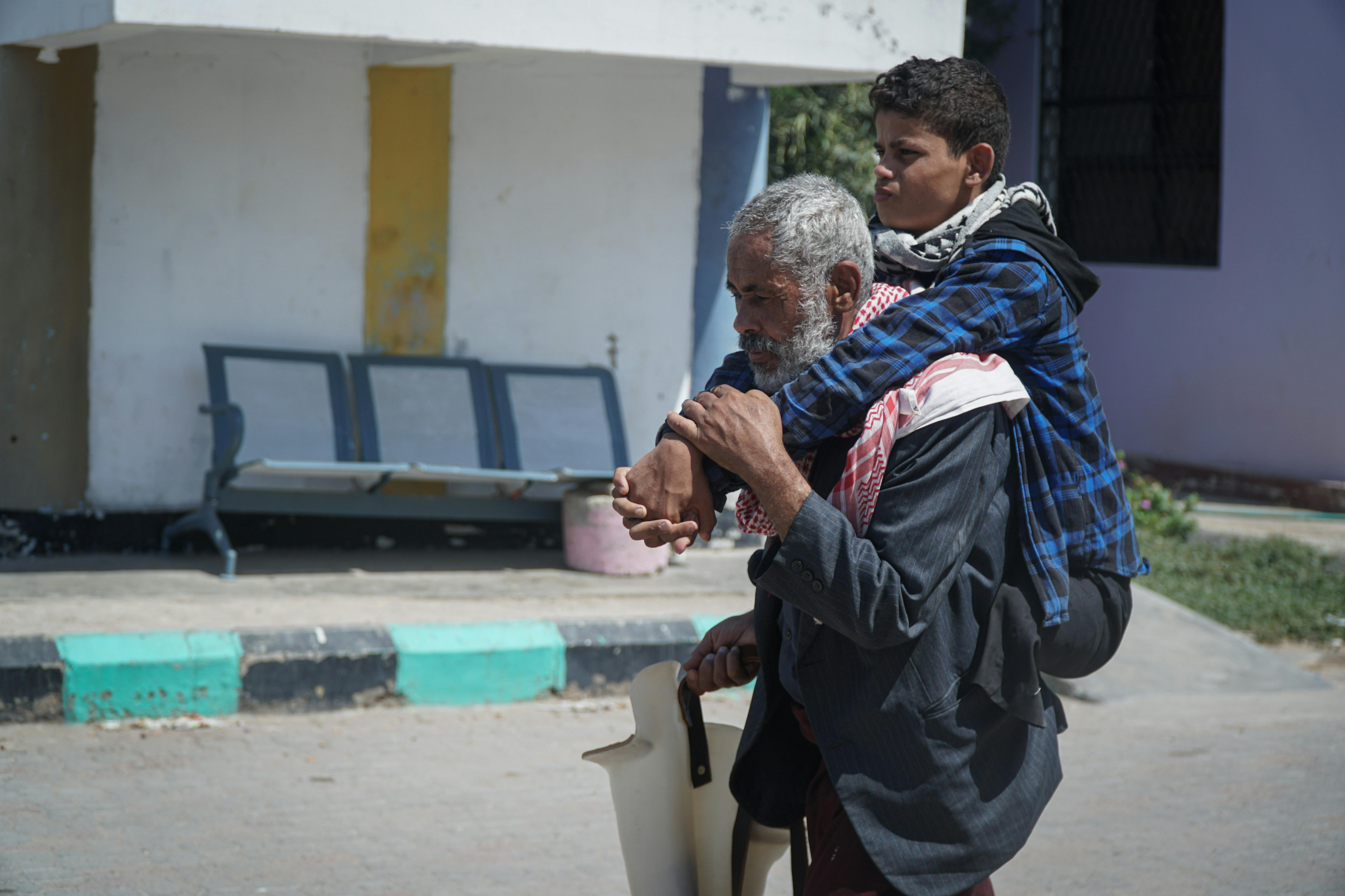 Ahmed Hassan Alwarafi porta suo figlio sulle spalle, Ibrahim, per arrivare al centro protesico di Aden, in Yemen