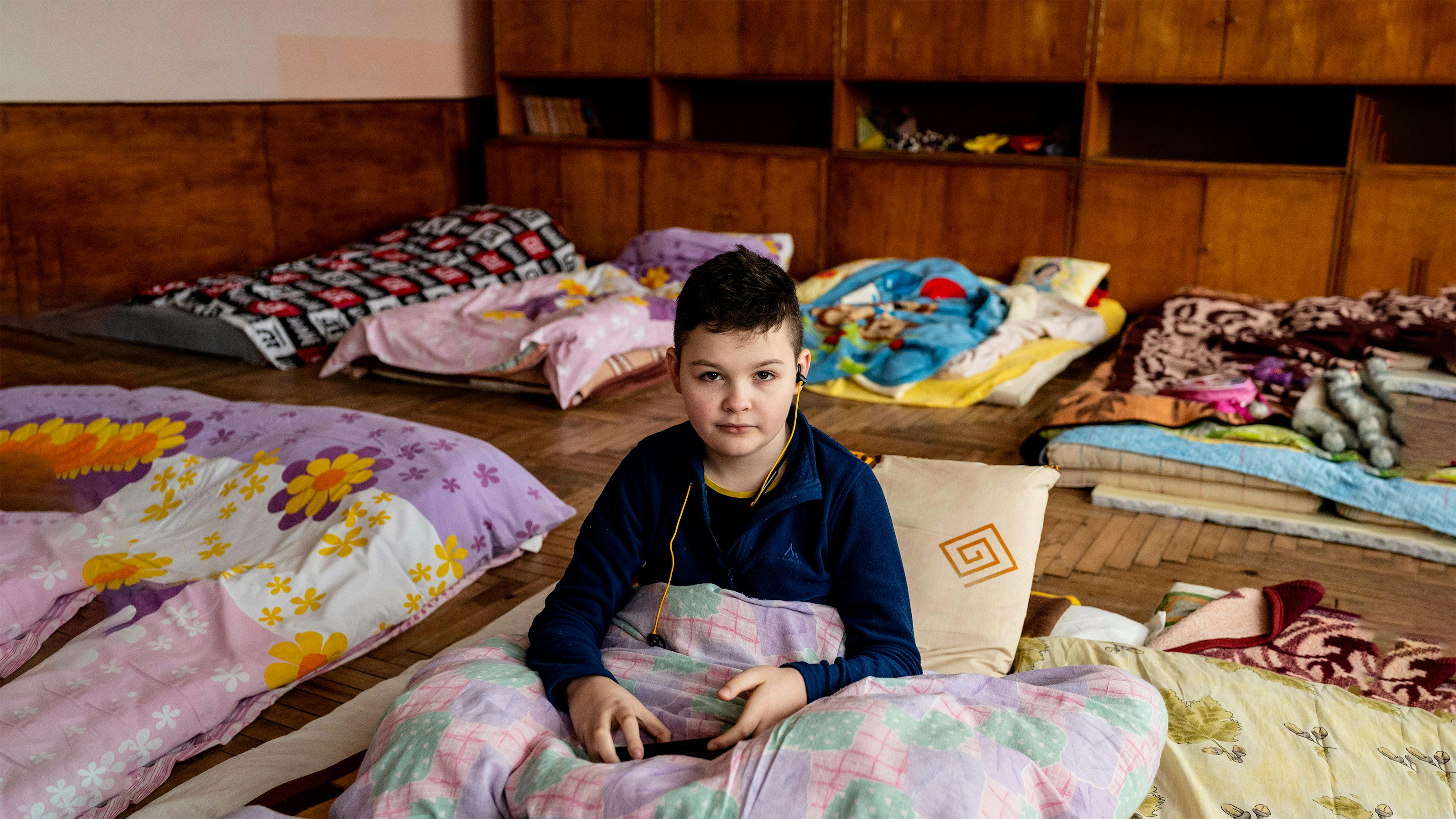 Ucraina, Roman (10) è seduto nel suo letto improvvisato in un'aula della scuola locale trasformata in centro di assistenza a Drohobych, nella regione di Lviv.