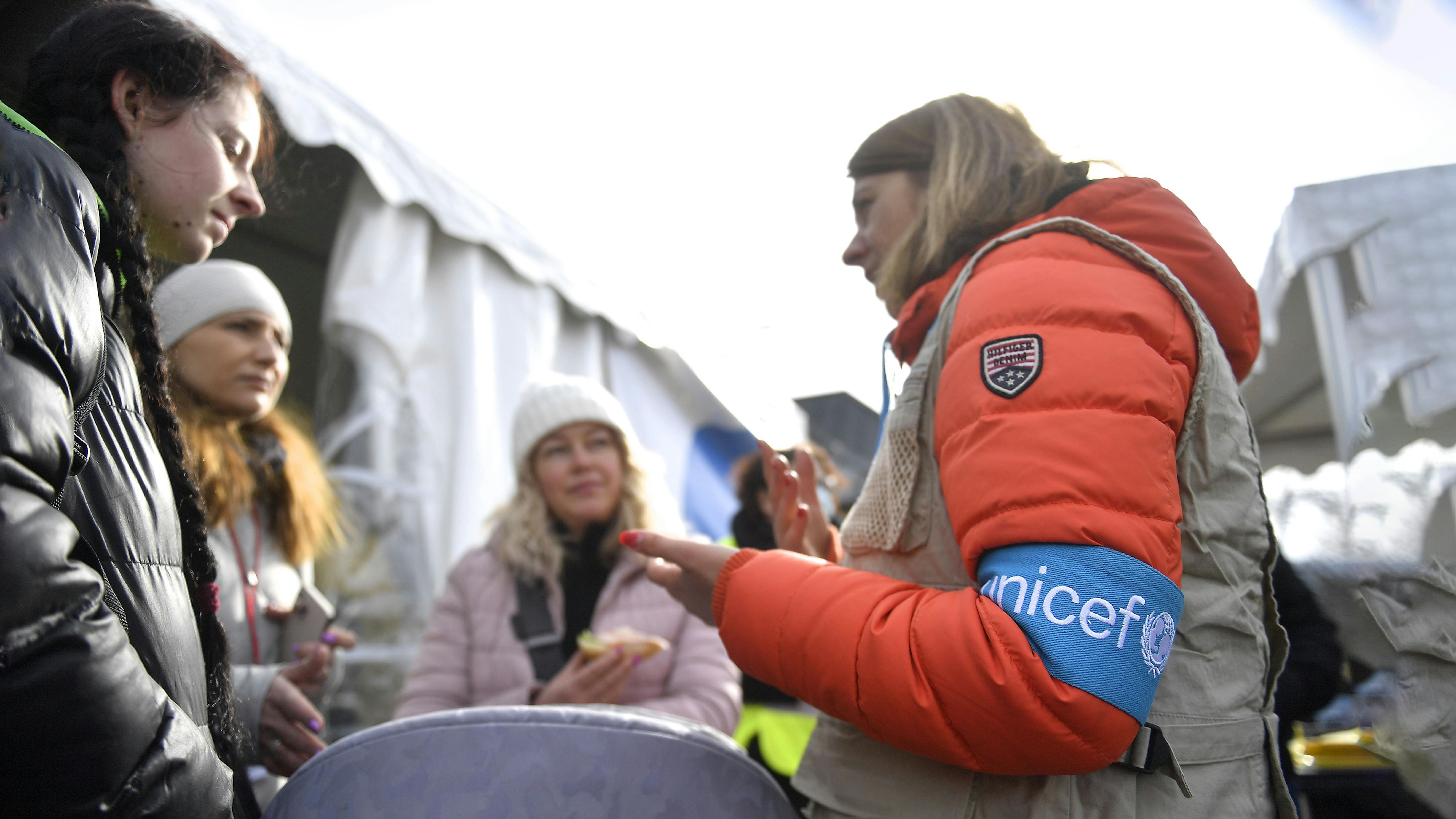 Un membro dello staff dell'UNICEF fornisce informazioni a un gruppo di rifugiati appena arrivati ​​in Romania