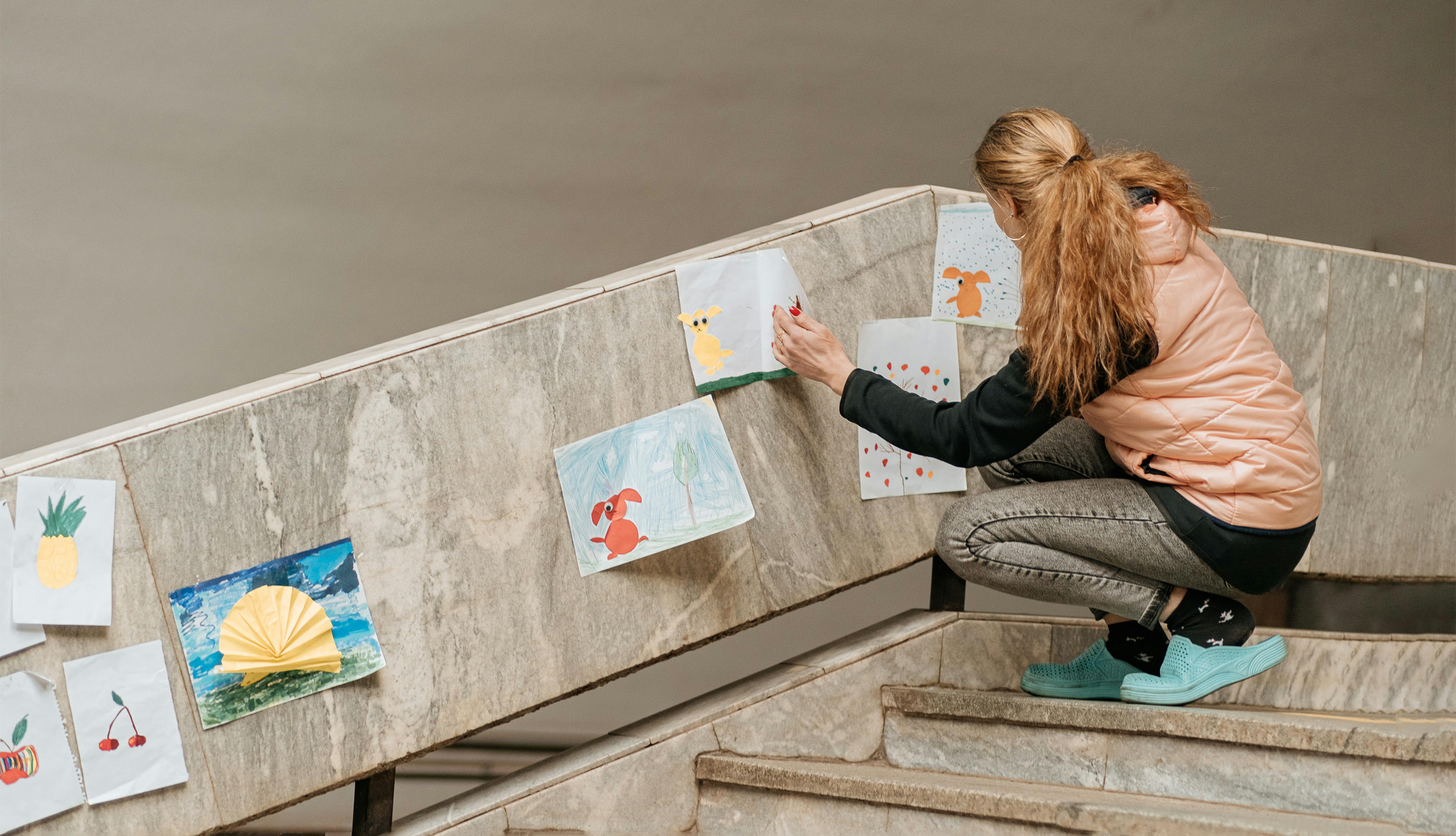 Kharkiv, una volontaria decora la scala di una stazione della metropolitana con disegni realizzati dai bambini durante un corso d'arte.