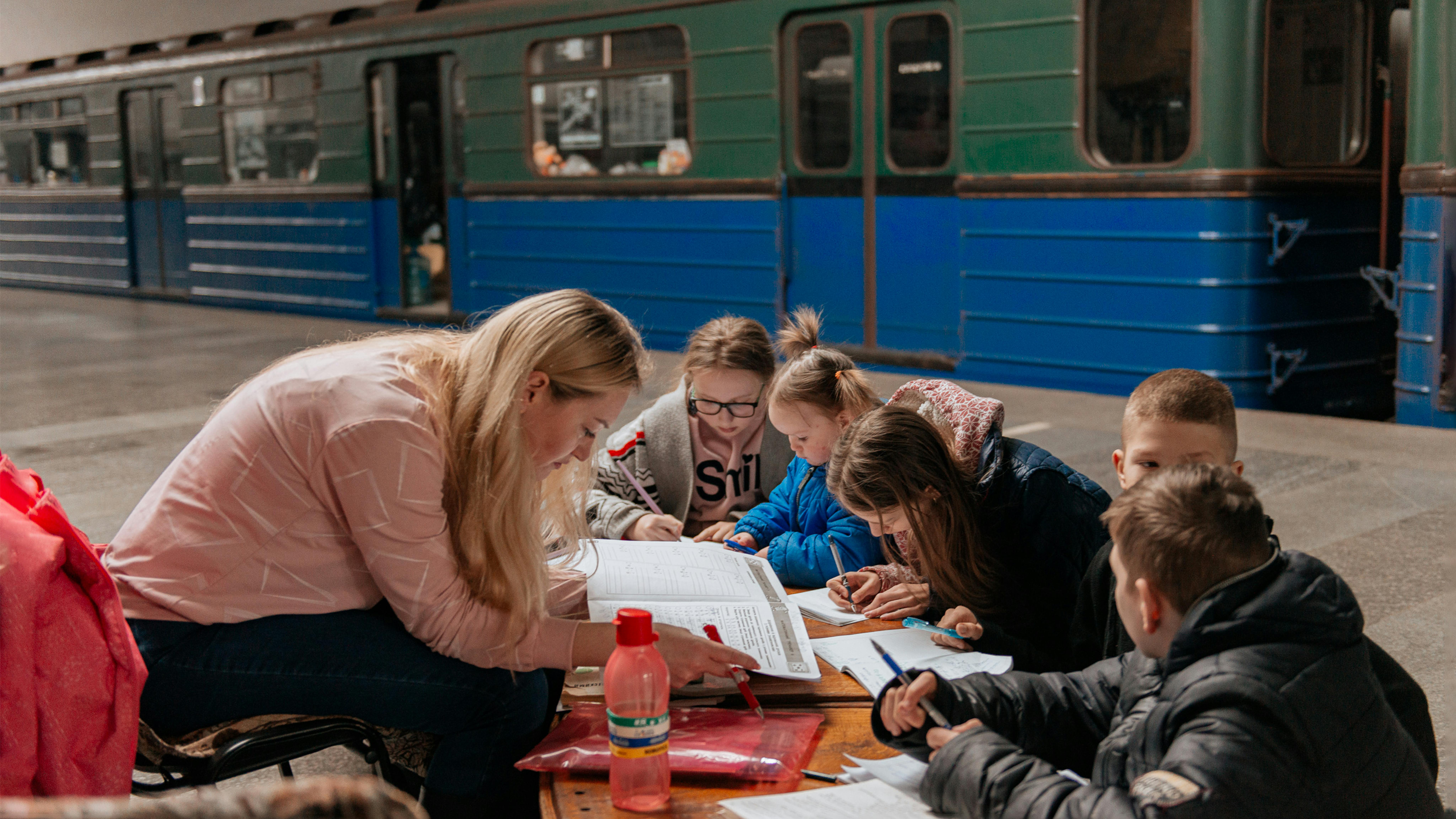 I bambini usano quaderni e cancelleria forniti dall'UNICEF per studiare nel rifugio/metropolitana di Kharkiv.  Finora, 4,3 milioni di bambini sono stati sfollati dalle loro case e altri milioni hanno un disperato bisogno di sicurezza, stabilità e protezione.