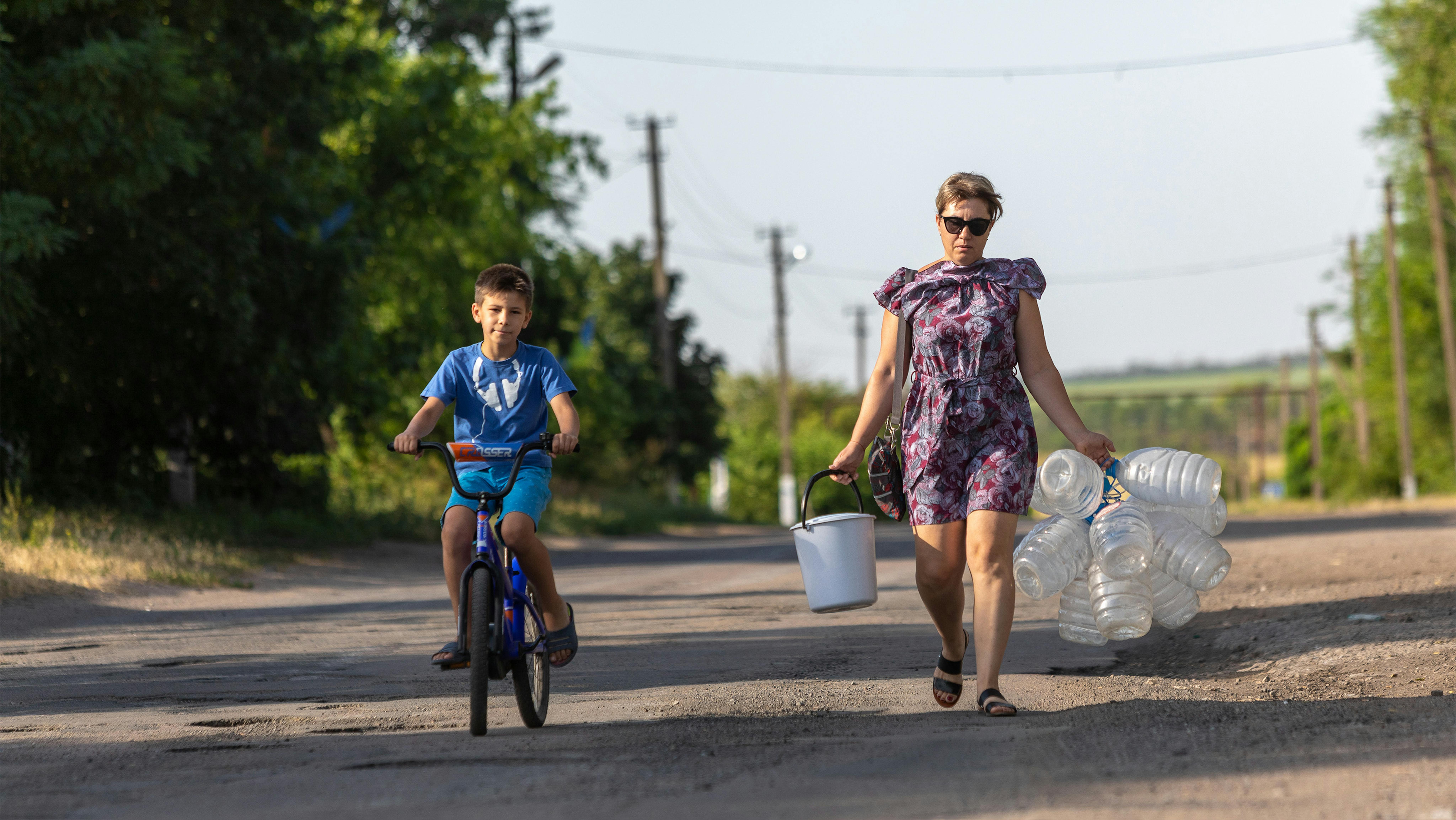 Una madre con il figlio portano contenitori vuoti  per essere riempiti d'acqua presso la stazione idrica di Paylopil