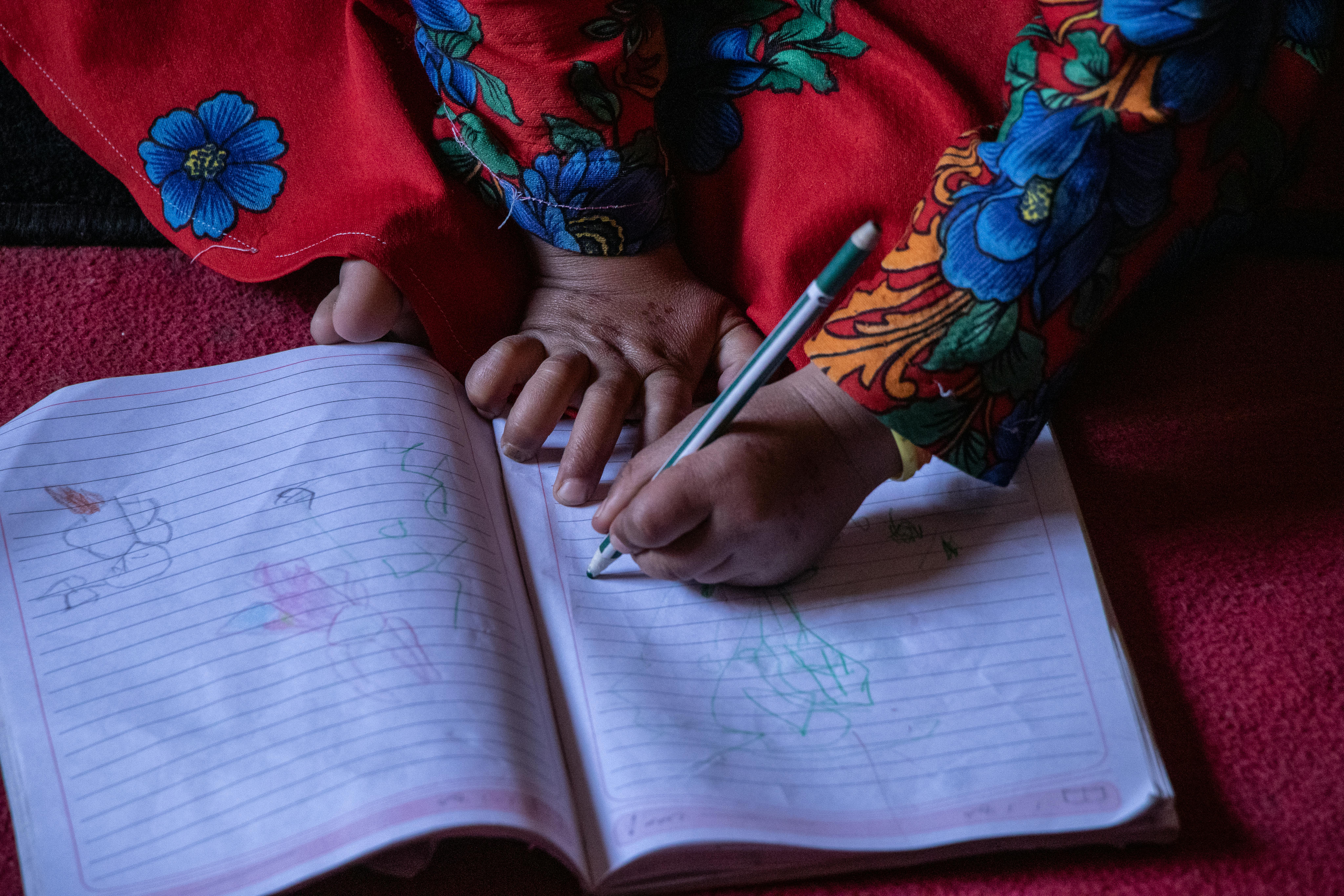 La piccola Farhana disegna su un quaderno. Dal giorno in cui il Comitato Protezione ha sventato il matrimonio forzato, lei e suo fratello frequentano gli spazi a misura di bambino dell'UNICEF