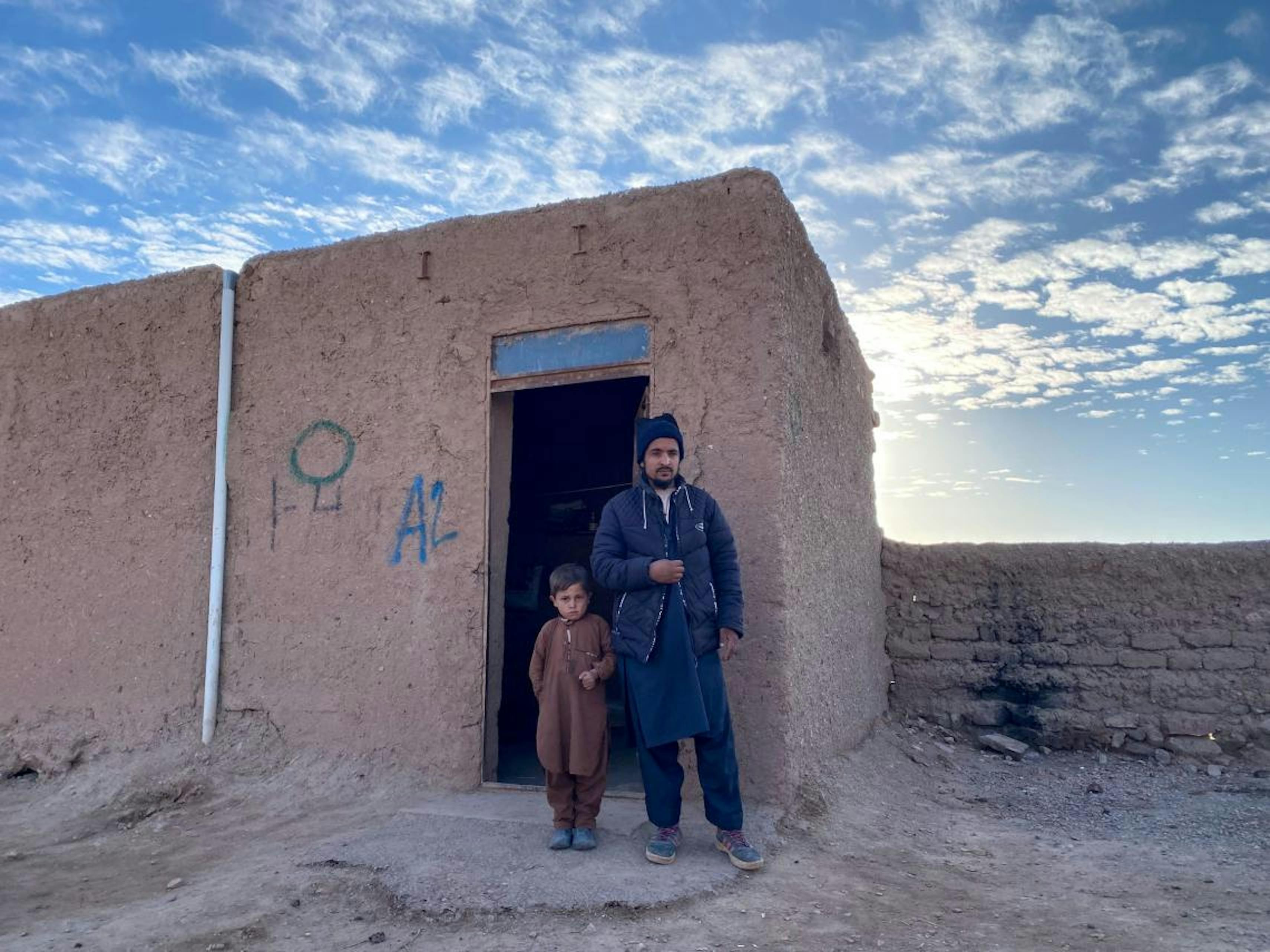 Karim con il figlio più grande, davanti alla loro casa di fango. Siamo nel campo per sfollati interni di Herat, in Afghanistan