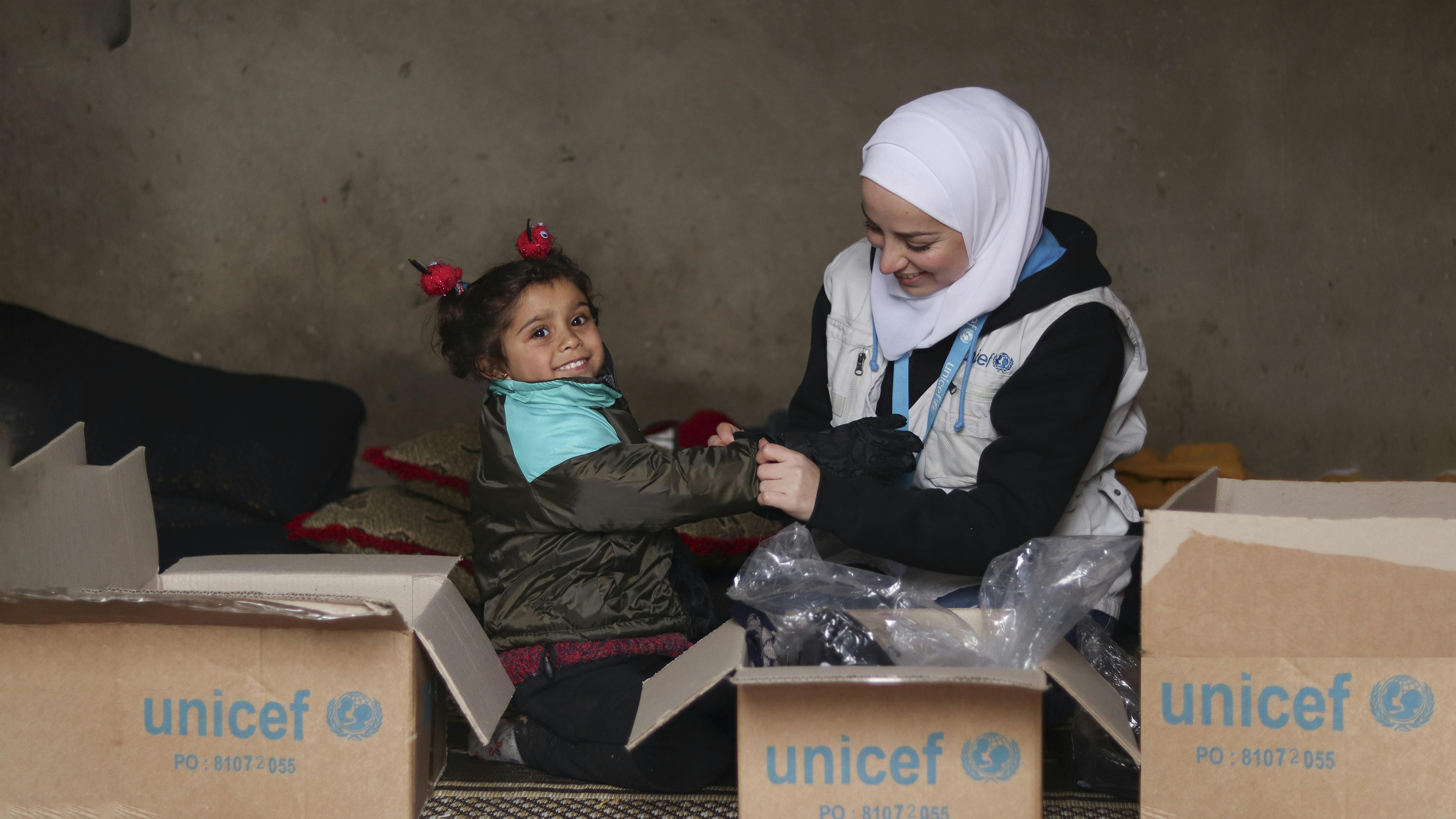 Siria, Un operatore dell'UNICEF aiuta una bambina ad aprire una scatola di provviste invernali nel villaggio di Ghernata