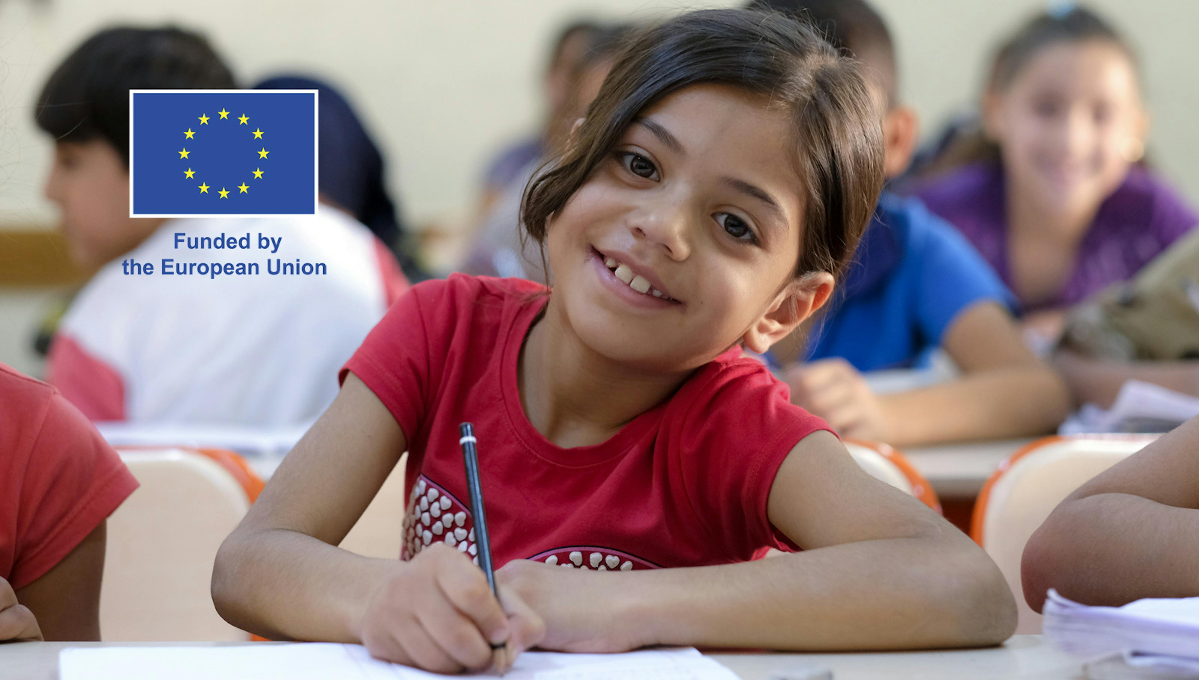 Una bambina siriana, rifugiata in Turchia, sorride mentre sta facendo i compiti in classe
