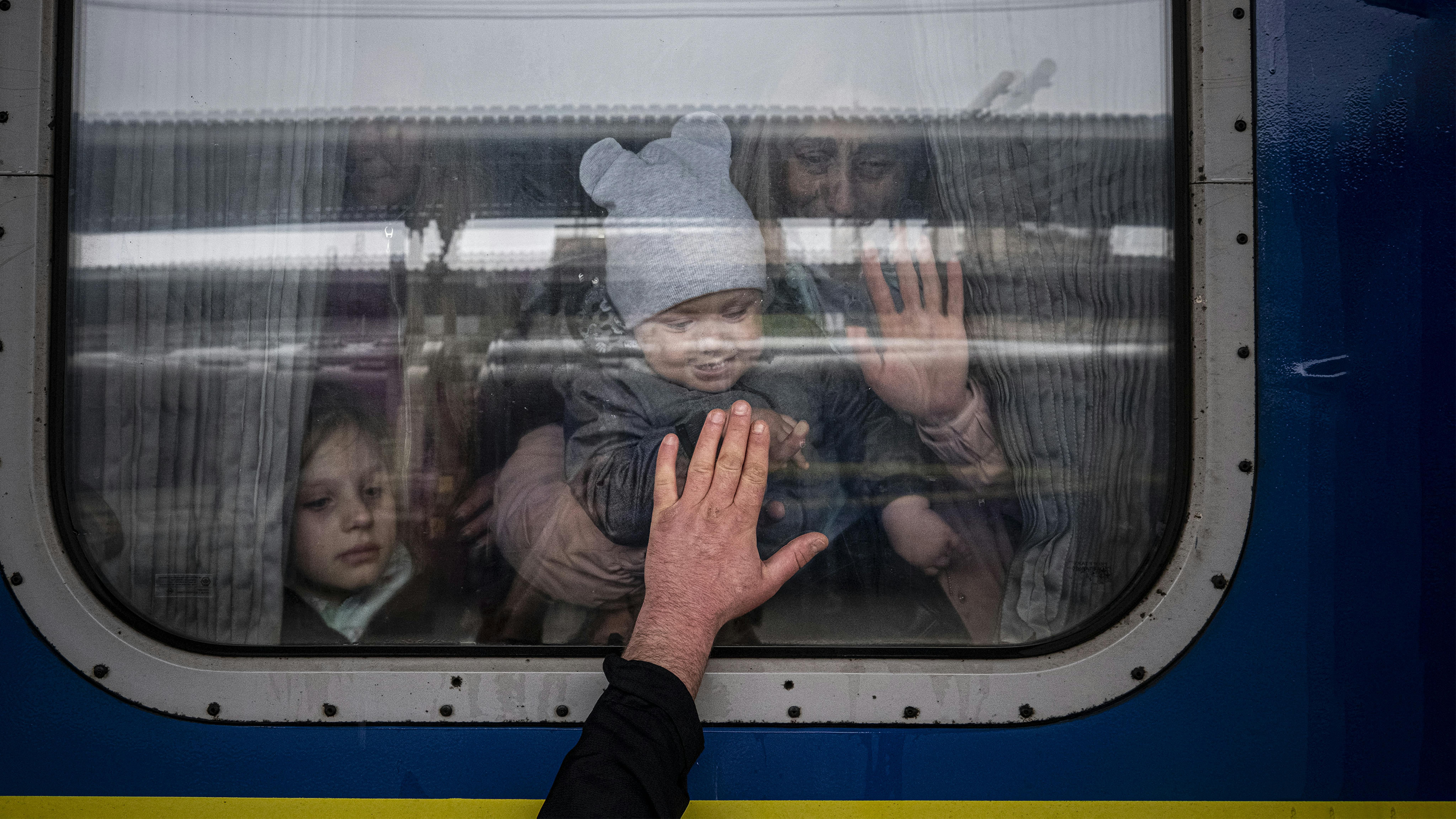 a Kharkiv, in Ucraina, un uomo mette la mano al finestrino di un vagone del treno mentre saluta sua moglie e i suoi figli prima che partano su uno speciale treno di evacuazione.