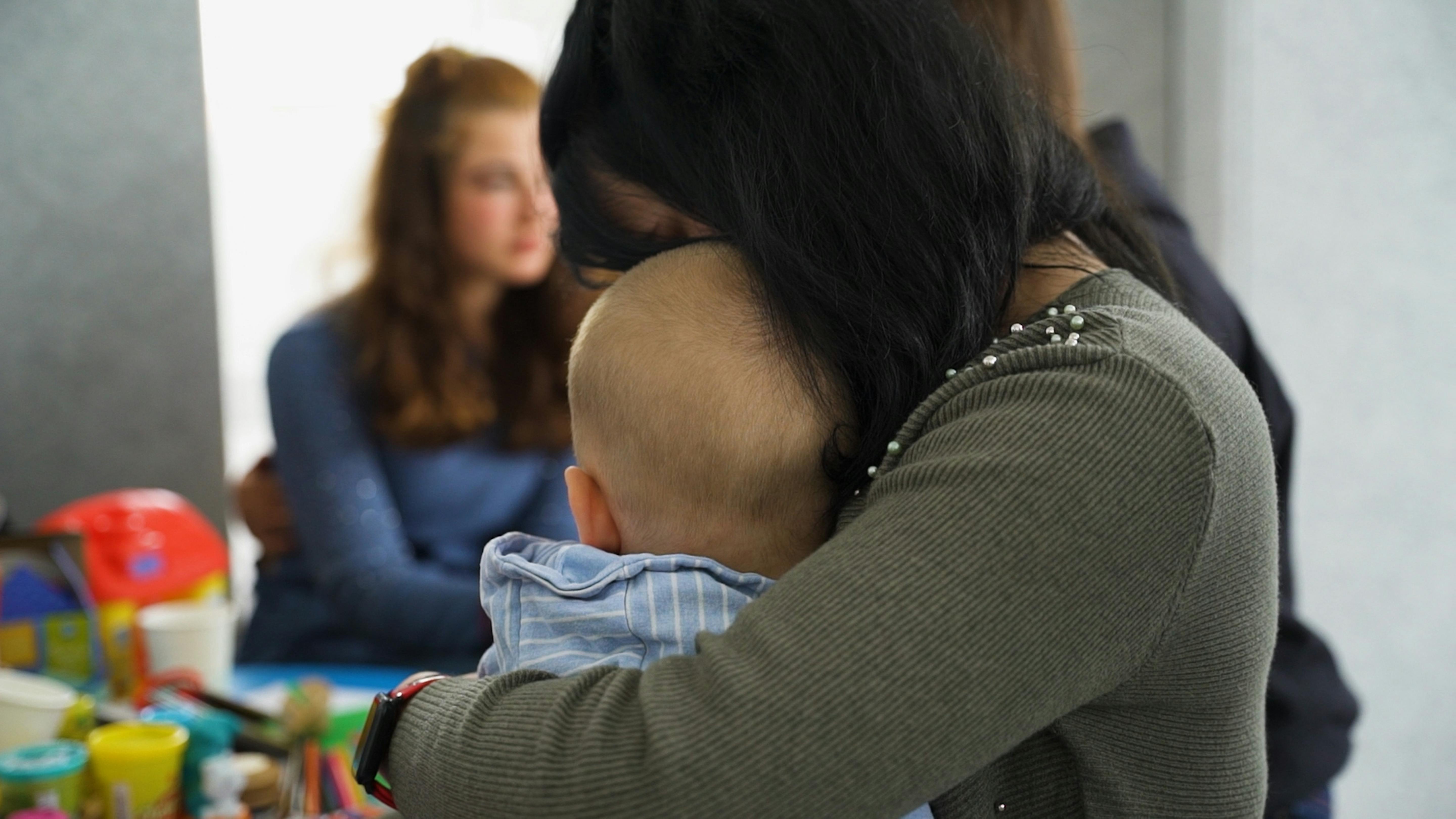 Una madre tiene in braccio il suo bambino mentre si trovano in uno di Blue Dot installati da UNICEF in Friuli Venezia Giulia