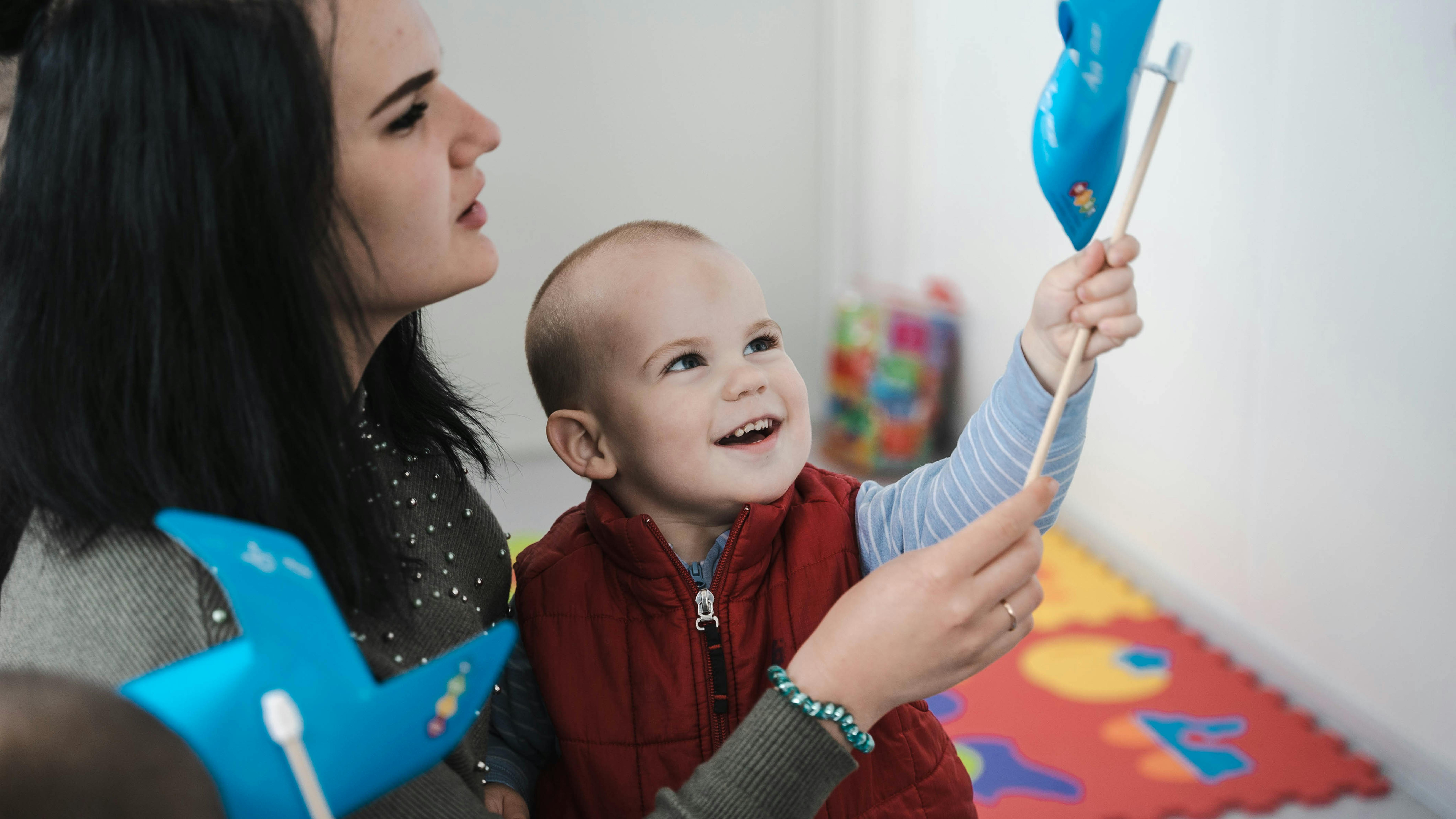 Mamma e bambino giocano con la girandola UNICEF in uno dei blue dot in Friuli Venezia Giulia