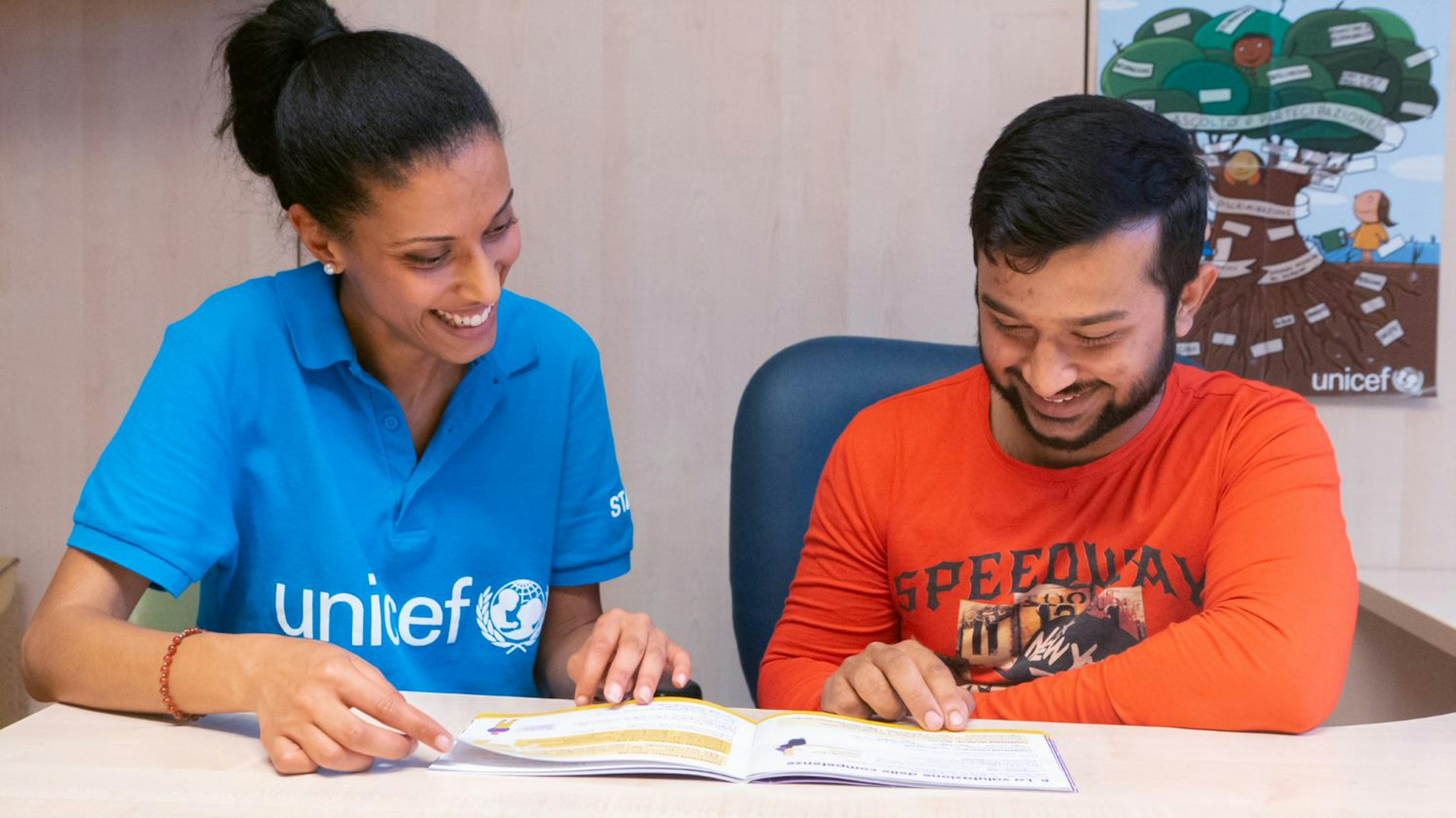 Un'operatrice UNICEF sfoglia il Vademecum insieme a un giovane migrante